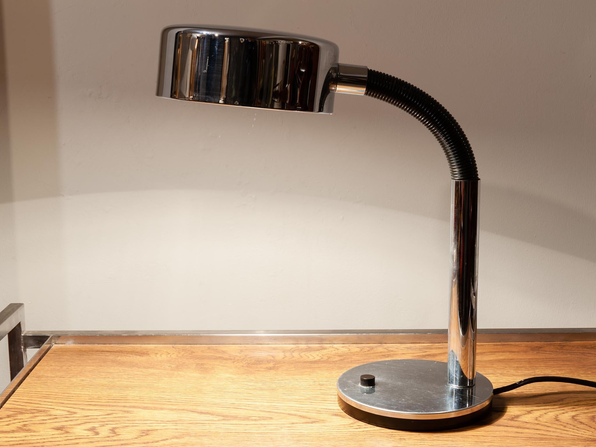 1970s flexible chrome and black desk lamp manufactured by Egon Hillebrand Leuchtenfabrik in Germany. The light sits on a chrome base with a small black on/off switch towards the front. The base supports the large chrome domed shade with a large
