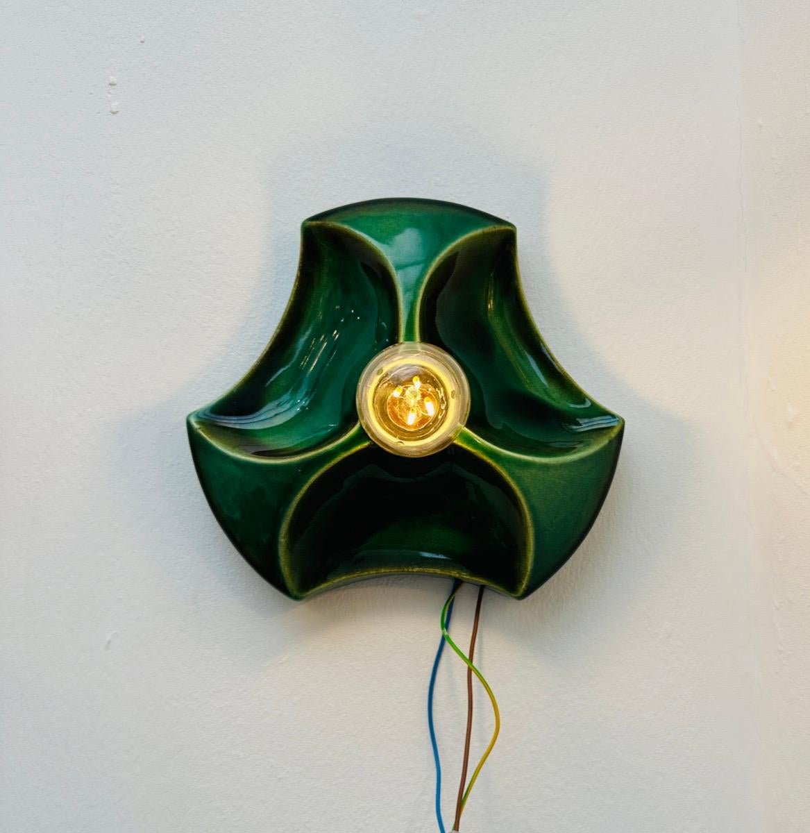 1970s vintage, retro, space-age, German Hustadt Leuchten 'Fat Lava' ceramic moss, pea and olive green glazed glossy wall sconce with a 3-dimensional design.  A single E14 screw in bulb sits in the centre of the triangular indented wall light.  I