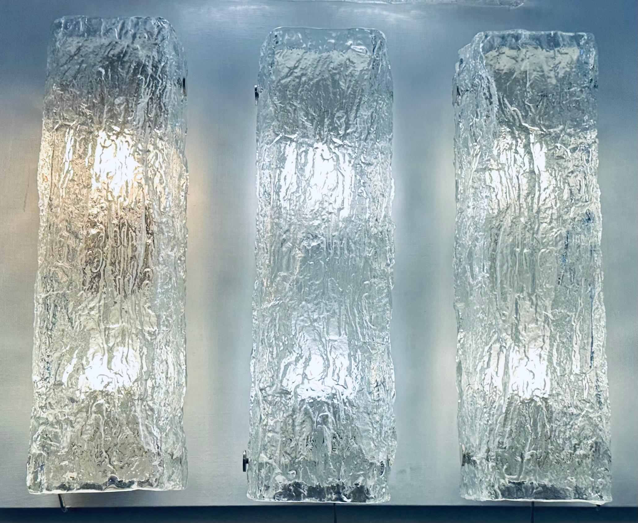 A set of 3 (priced individually) 1970s iced-glass textured wall sconces or wall lights manufactured by the upmarket German light manufacturer Kaiser Leuchten. The rectangular thick textured glass screws onto a white lacquered metal frame which is