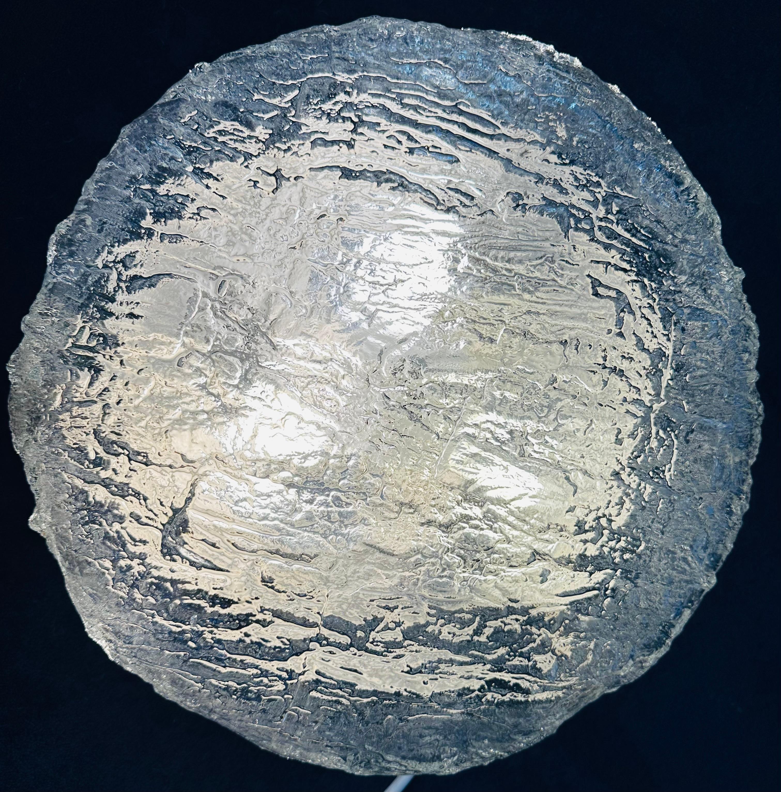 1970s circular flush mount ceiling light manufactured by Kaiser Leuchten in Germany.  the manufacturer's label is still present on the metal frame.

The heavily textured circular clear glass shade is made from a single piece of glass which is folded