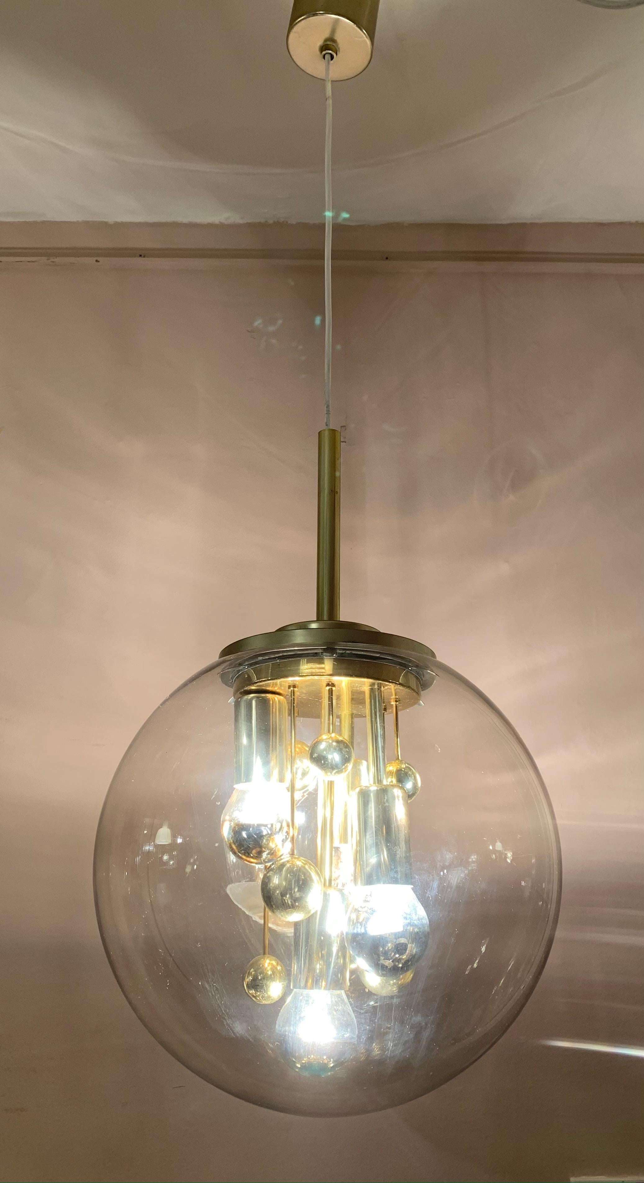 Circa 1970s large globe pendant hanging light which was manufactured by Doria Leuchten in Germany. The brass fitting that sits inside the smoked-glass hand blown globe has vertical rods of different sizes and lengths with spheres at the end of each