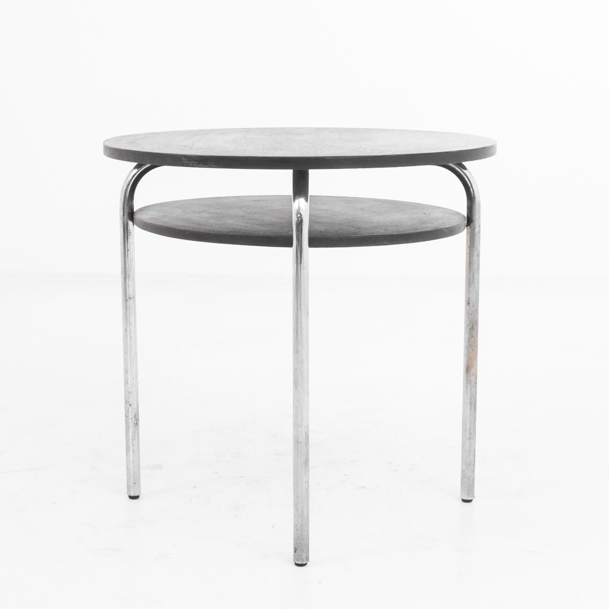 This 1970s German Metal Round Side Table with a Wooden Top is a striking blend of rustic charm and industrial design. The sleek metal legs have a raw, unfinished look that contrasts beautifully with the dark, circular wooden top. The aged patina of