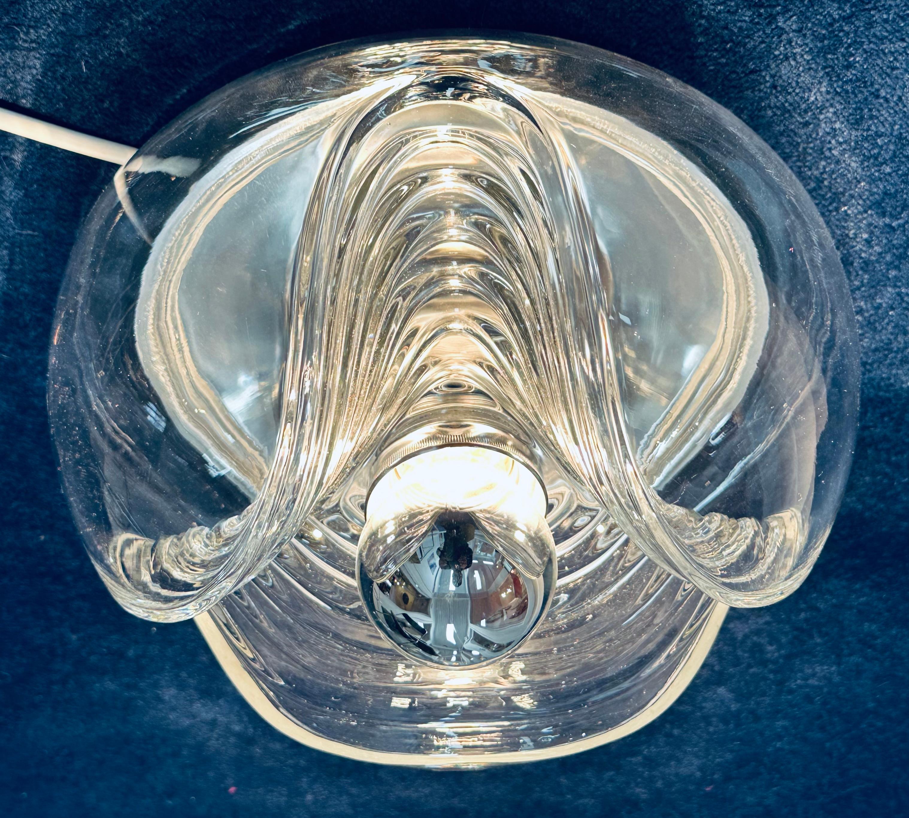 An absolutely beautiful 1970s 'Wave' clear ribbed glass wall or flush mount ceiling light with a polished chrome reflective base plate designed by Kock and Lowy for Peill & Putzler Germany.  A very unusual design with 'waves' of ribbed glass on the