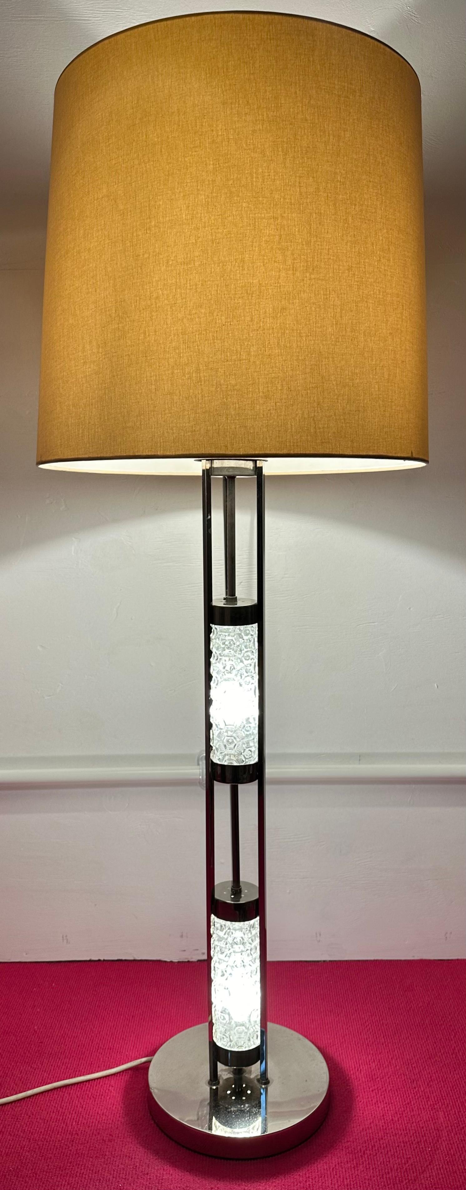 A striking mid century polished chromed-metal and structured abstract glass floor or table lamp designed by Richard Essig for Besigheim in Germany during the 1970s. The lamp stand illuminates in two sections which are separated by a chrome ring and