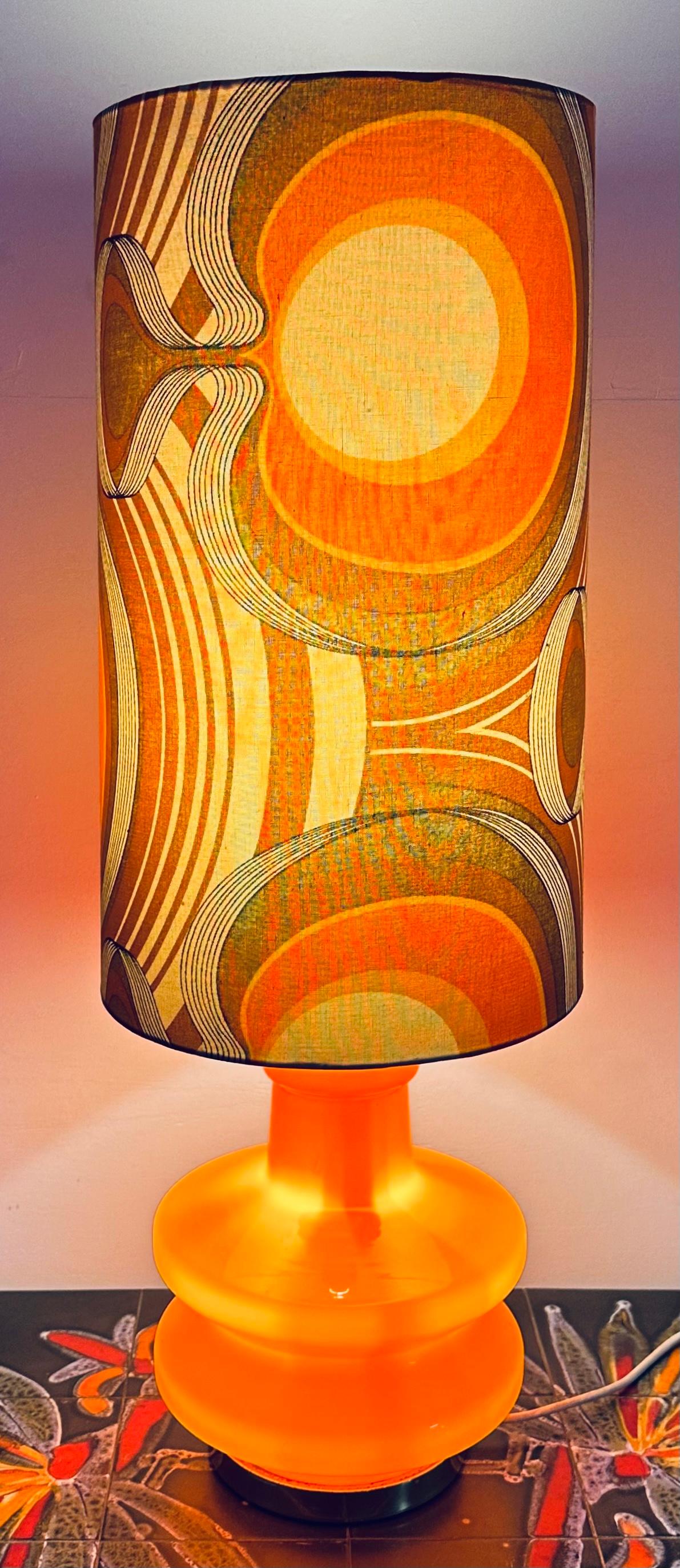 1970s German space-age and futuristic illuminated orange glass table lamp.  The illuminated orange base with feature brass fittings requires a single E14 screw-in bulb inside.  This is accessed by unscrewing the brass screw below the lightbulb