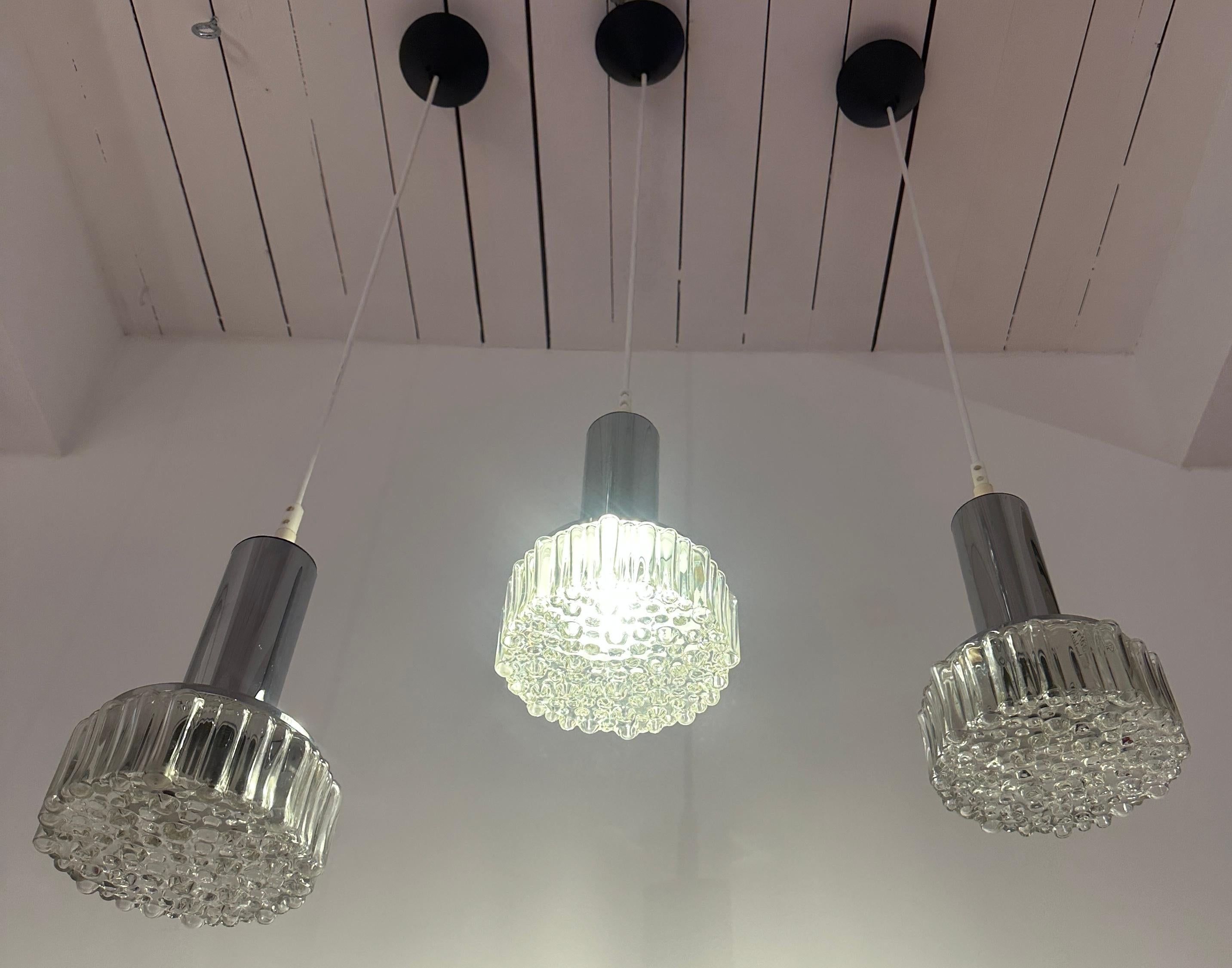 Suspension en chrome poli et verre clair de la marque allemande Staff Leuchten, datant des années 1970.  Modèle n° P105.  Conçu par Rolf Krüger et fabriqué par Staff Leuchten.  

Les abat-jours en verre se clipsent sur le support d'ampoule tubulaire