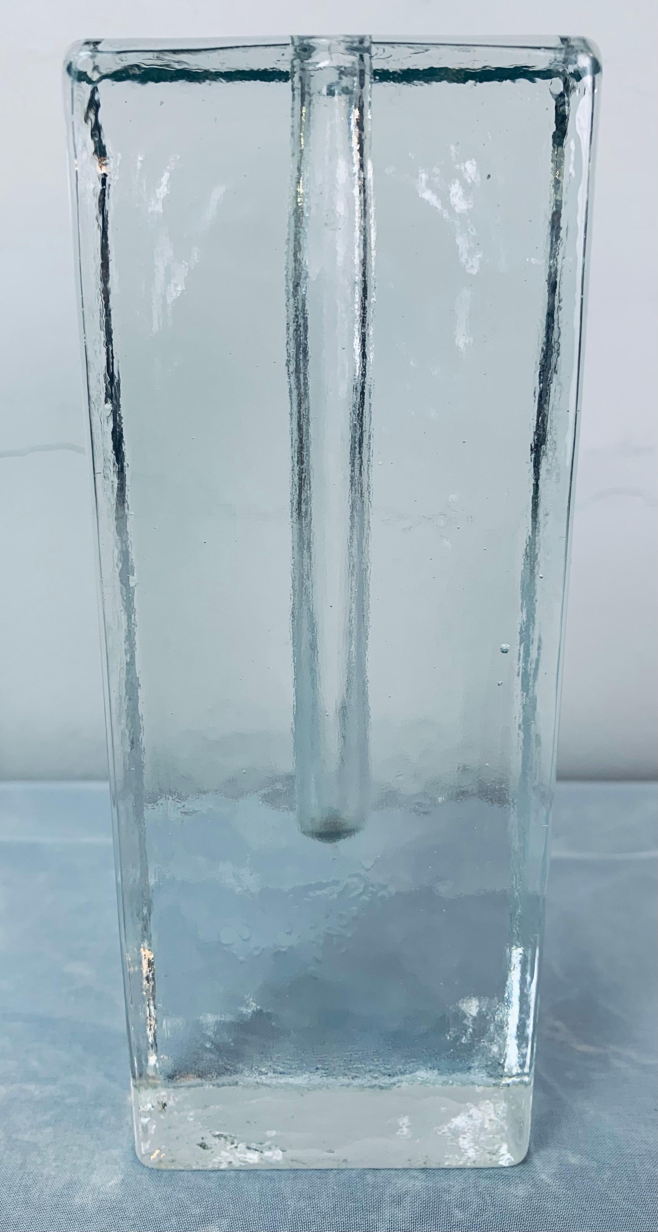 1970s German Solifleur rectangular solid glass vase.  The tall version is made from a solid block of slightly textured glass with a hole in the centre for the flower to be placed or nowadays perhaps a slim candle. The vase was designed by Klaus