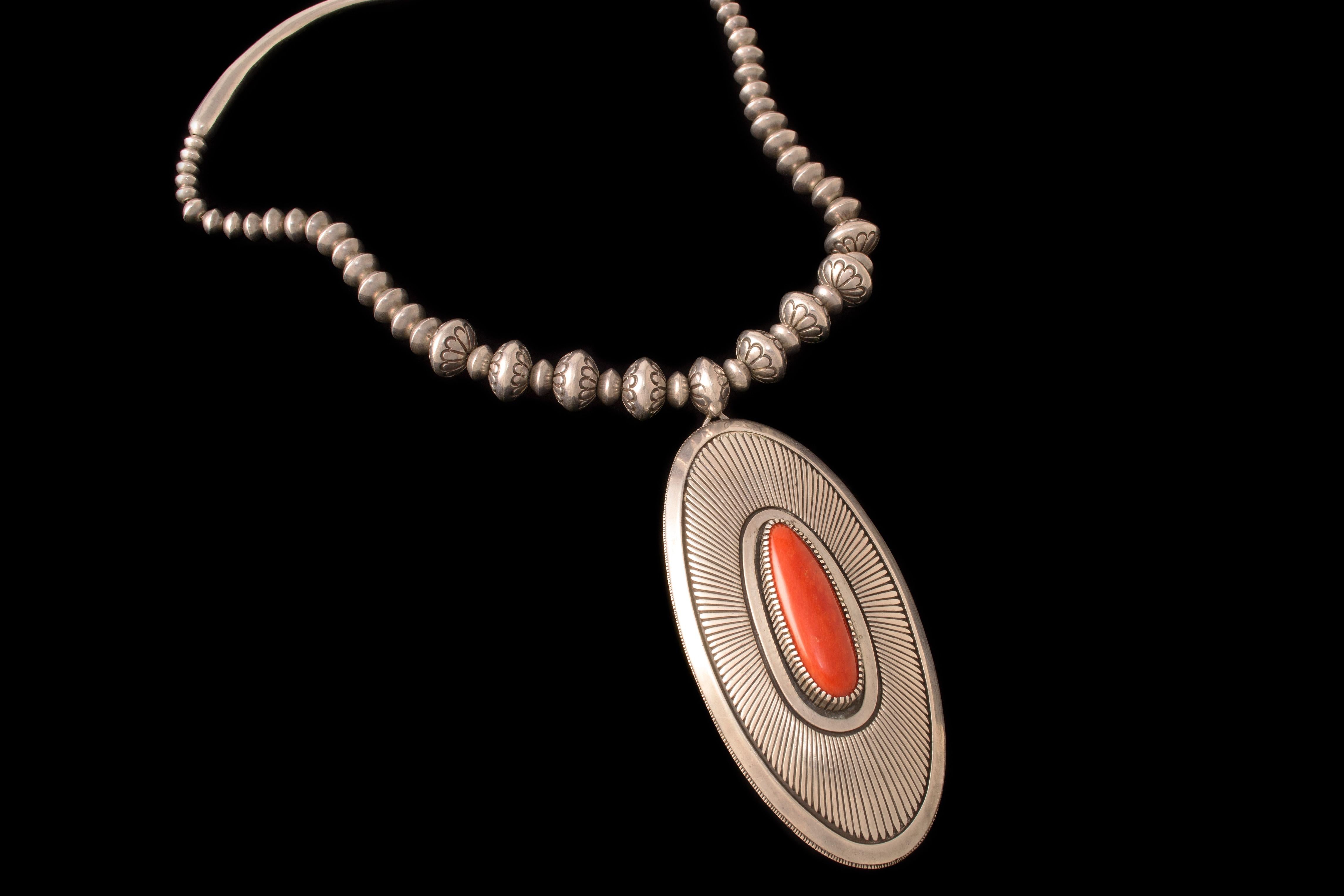 A coral cabochon and stamped sterling silver bead necklace, by Gibson Nez, c. 1970. 

The length of the necklace is 19