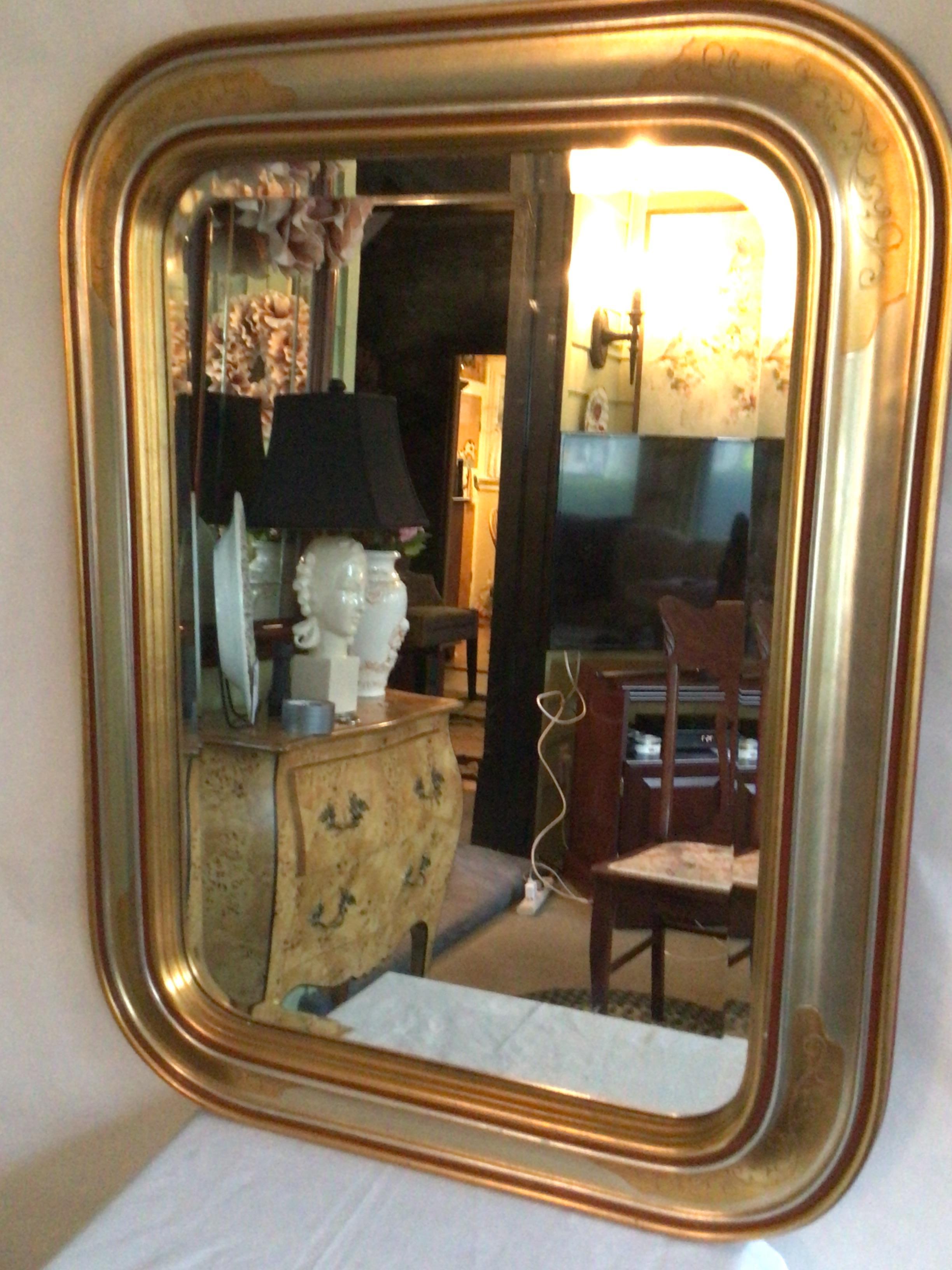 1970s Gilt and Silver Leaf Wood Wall Mirror With Beveled Glass
Wood base
Beveled glass mirror
Painted Scroll Detail at Rounded Corners
