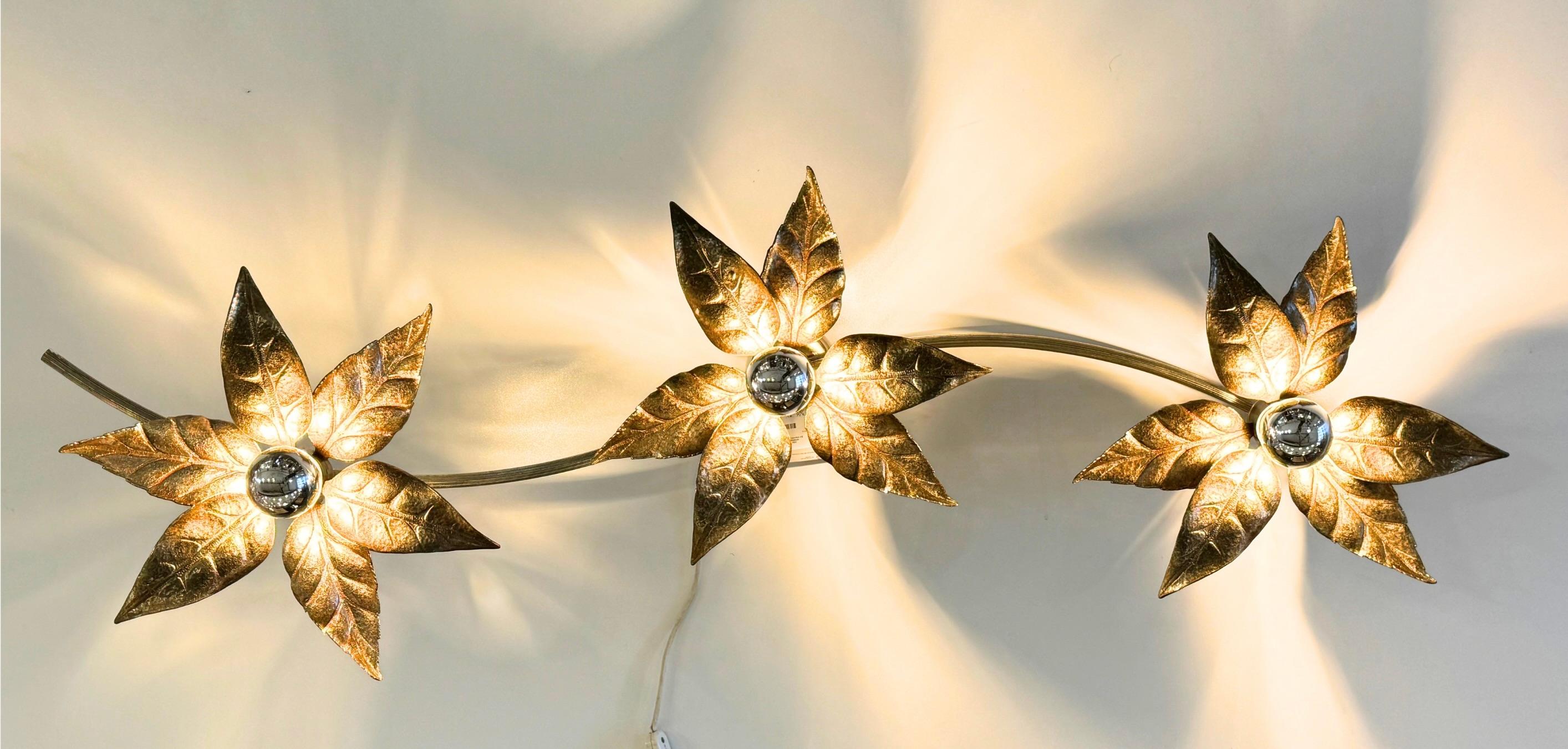 Hollywood regency wall lamp by Willy Daro for Massive Lighting Belgium, circa 1970s.
Consists of 3 light points with organic form gilt brass flower diffusers, mounted on a brass rod.
Large wall sconce, quintessential of the hollywood regency