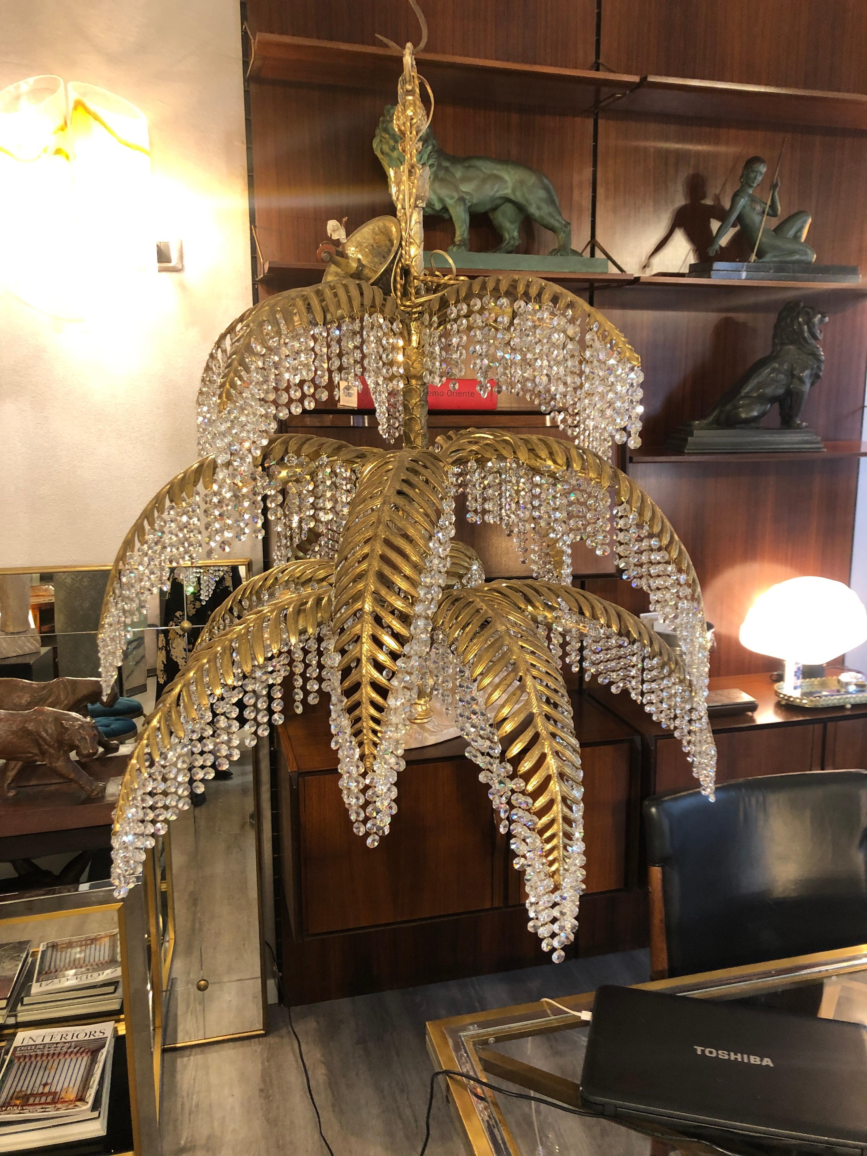 Golden bronze and crystal palm tree chandelier by Bakalowits, Austria, circa 1970s inspired by Hoffmann design. This chandelier is composed by the finely worked central trunk from which the leaves start. Many chains of crystal drops are hung to Each