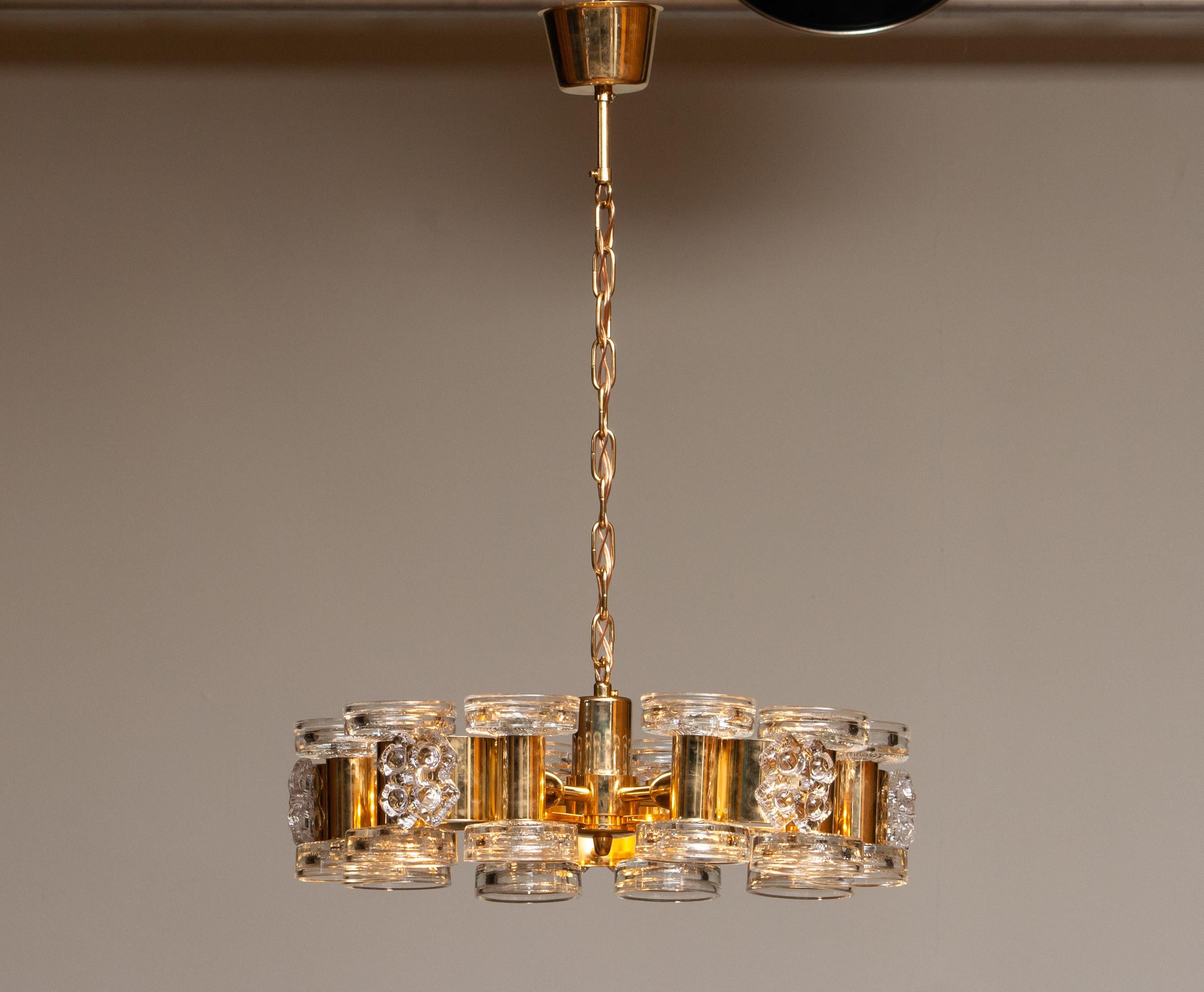A gilt chandelier with ten glass candleholders glass  on top and five internal screw bulbs, designed by Carl Fagerlund for Orrefors, Sweden, in the 1970s. The chandelier is in good overall condition and is technically fully functional. It