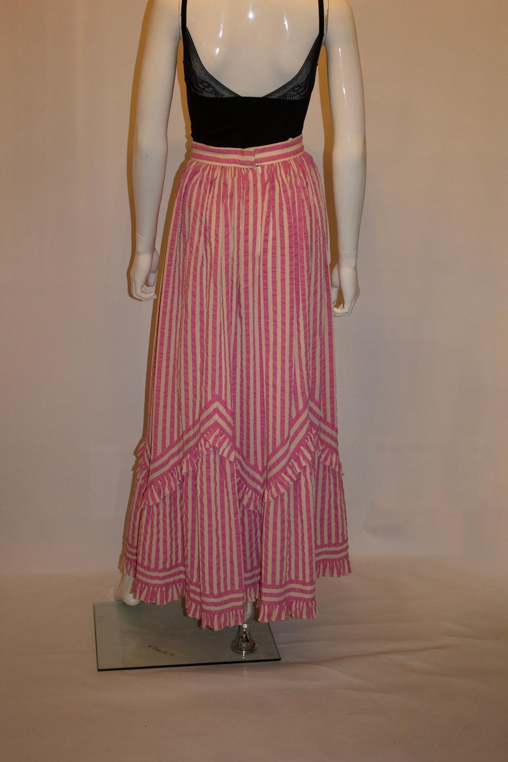 Una bellissima gonna vintage di Gina Fratini. In un tessuto a righe bianche e rosa con strisce che vanno in direzioni diverse, la gonna è perfetta per le vacanze e gli eventi. Ha un volant sull'orlo ed è completamente foderato. Vita 25'', lunghezza