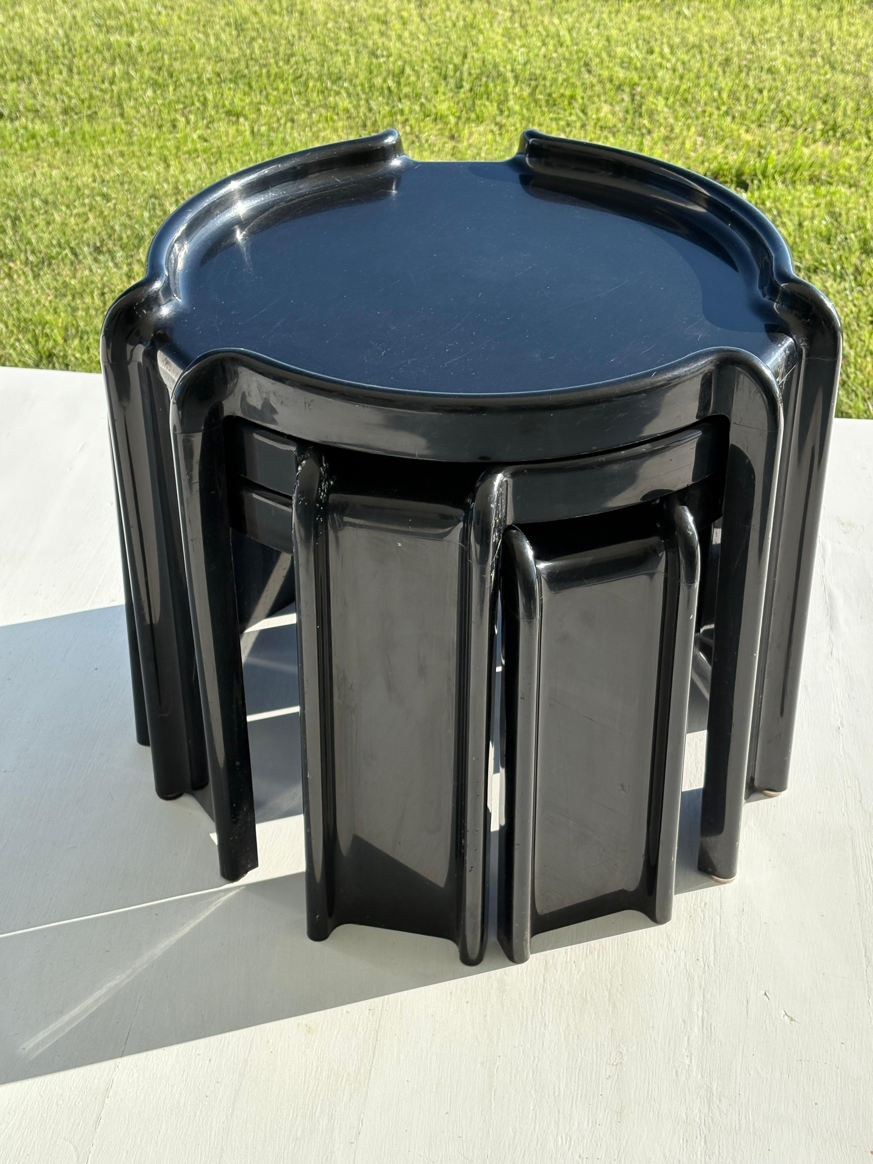 Icónico juego de 3 mesas auxiliares apilables redondas de plástico negro. Diseñadas en los años 70 por Giotto Stoppino para Kartell. En  las partes superiores de las mesas tienen todas las mismas dimensiones con bordes redondeados elevados y patas