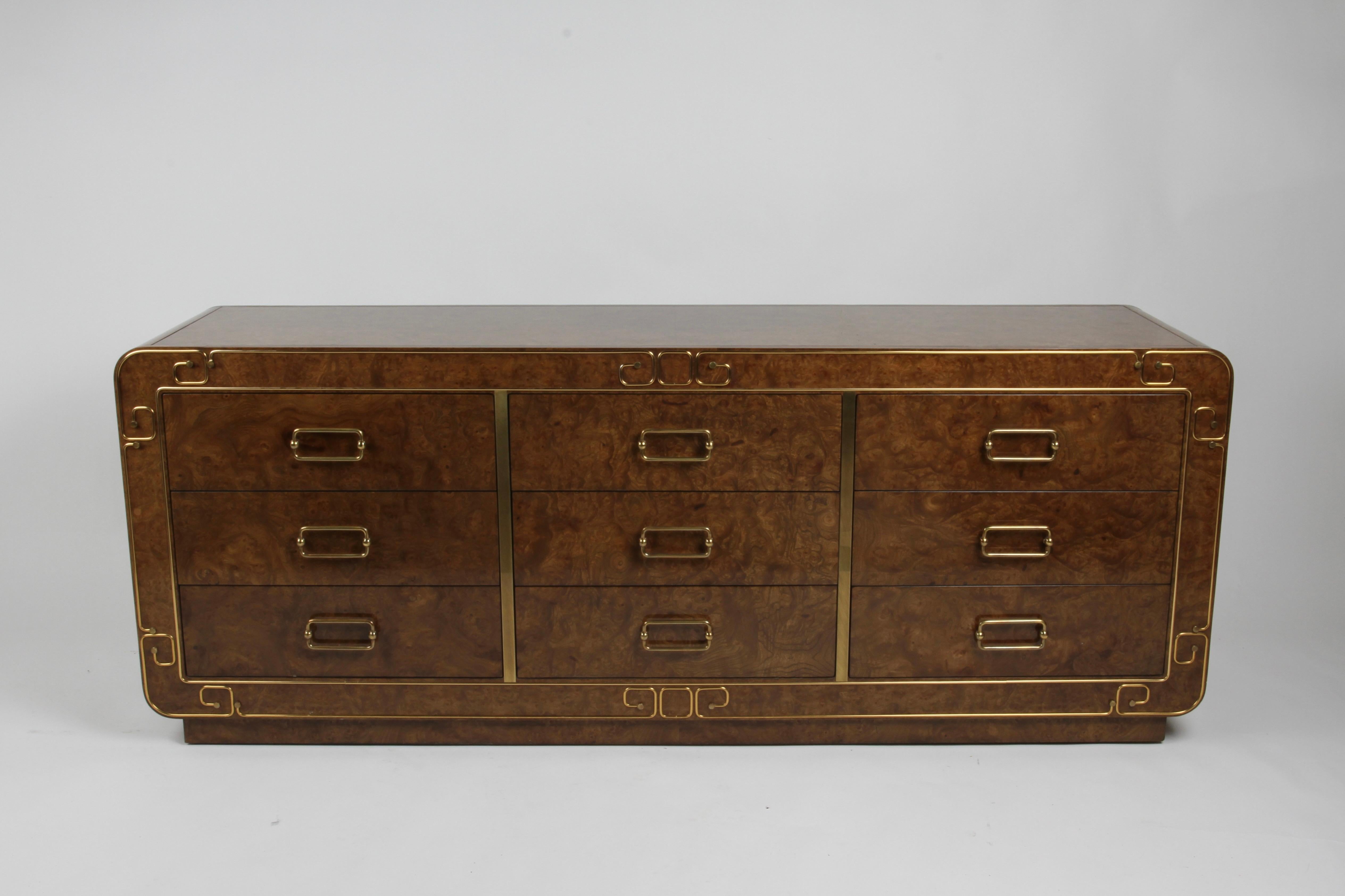 Impressive Mid-Century Modern or Hollywood Regency 1970s Mastercraft nine drawer dresser / sideboard in Burled Elm, with brass inlay, floats on plinth base. Drawers are dovetailed, custom brass handles and brass trim around front of case forms Greek