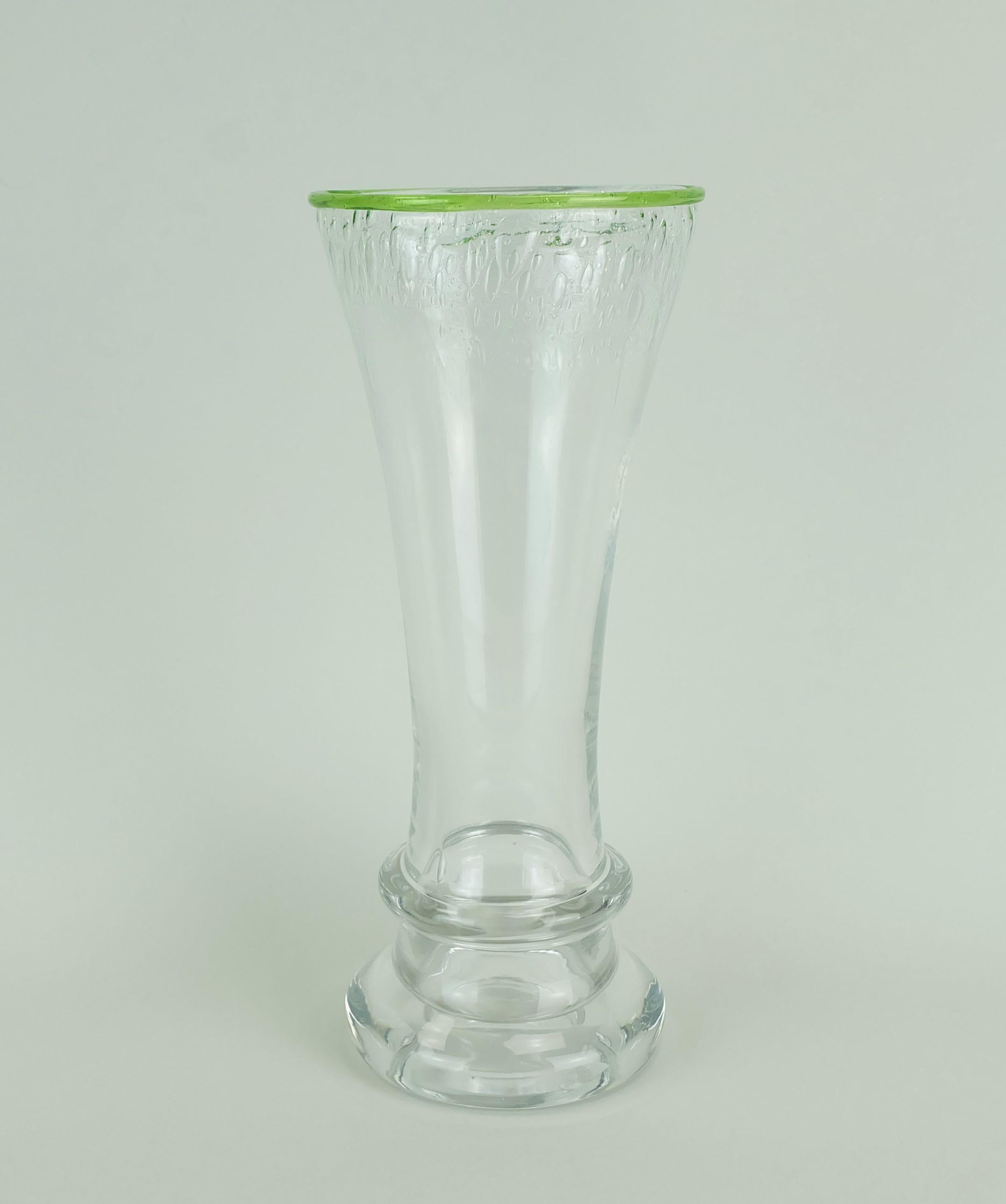 Un vaso in vetro molto decorativo degli anni '70 prodotto da Eisch Germany. Vetro spesso e trasparente con bolle d'aria nella parte superiore e bordo verde. 

Dimensioni in cm:
Altezza 25 cm, diametro del piano 10,7 cm, diametro del supporto 9,5 cm.