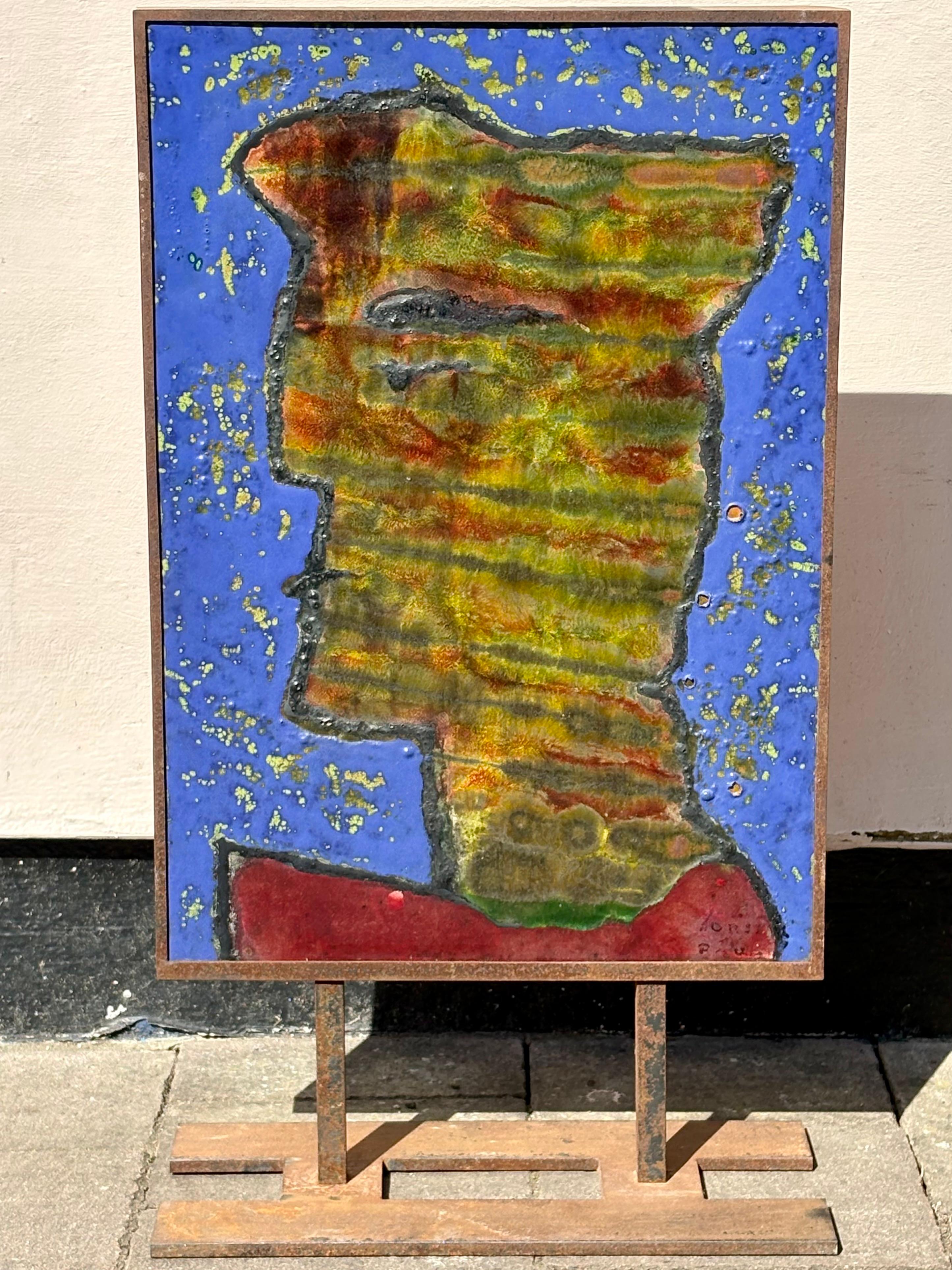 Raffigurazione stilistica di una figura indistintamente firmata . Realizzato in ceramica e smaltato in un colore ricco e meraviglioso, è incastonato in un supporto di ferro con schienale in compensato. 