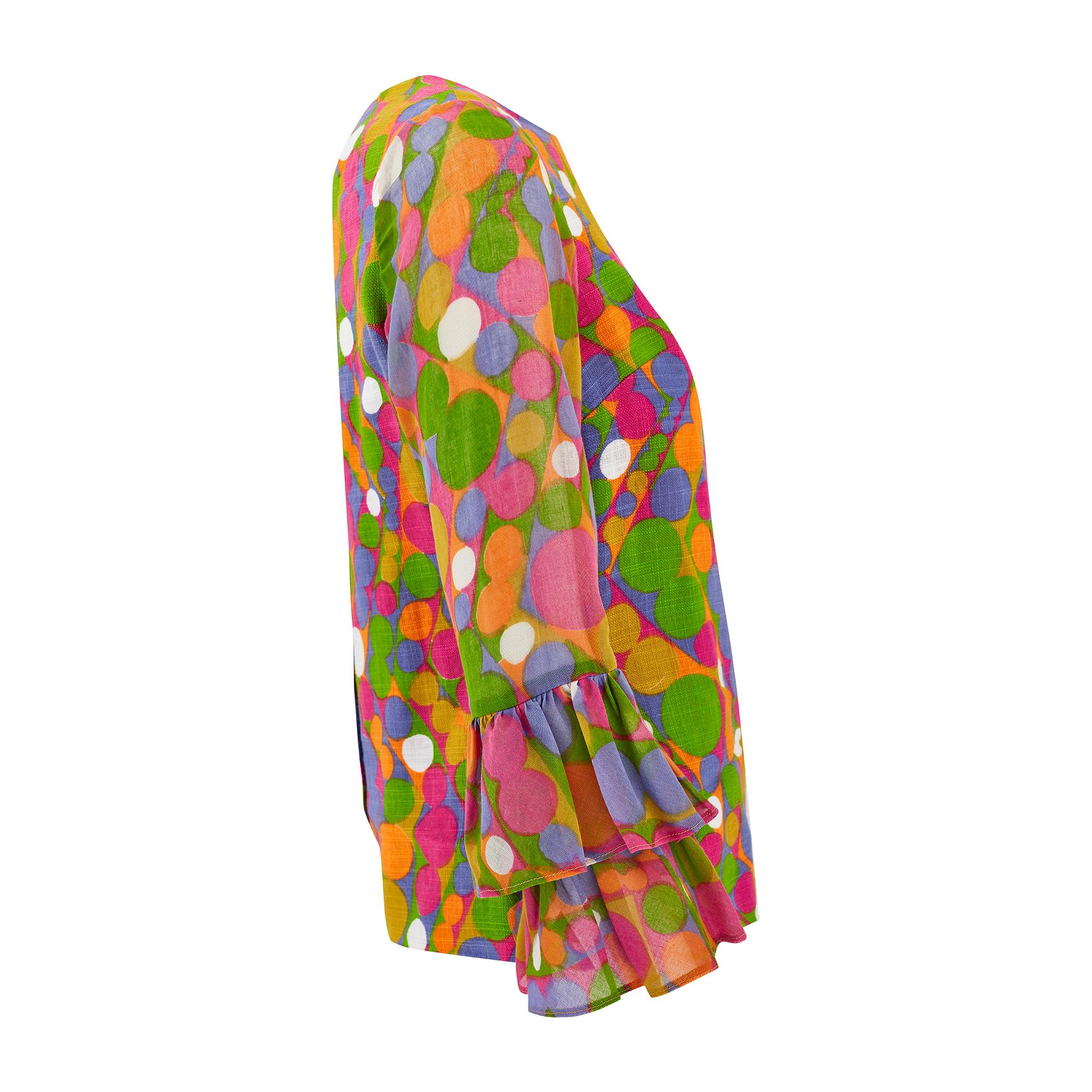 A great example of early 1970s daywear, this blouse was designed by Glen Sportique. Tailored from linen and cotton fabrics, and printed with polka dots arranged in a zig-zag formation in fuchsia pink, apple green, mustard, orange, lilac and white.