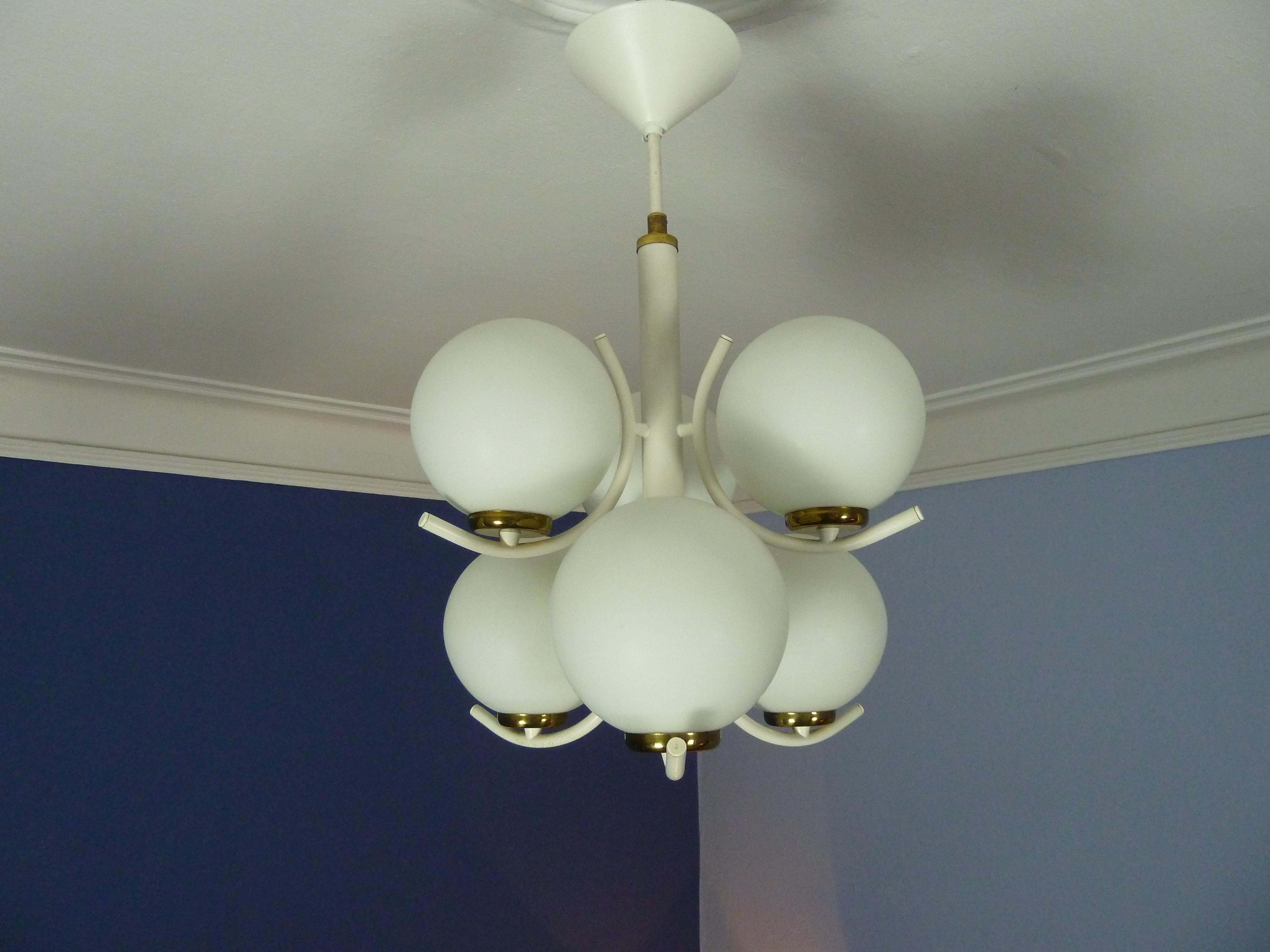 A elegant midcentury 1970s opaline glas modernist chandelier.
 White lacquered steel, opaline glas, and some nice details in brass.
A 1970s interpretation of Art deco.


The fixture has 6 sockets for Edison E14 Bulbs.
The color and light