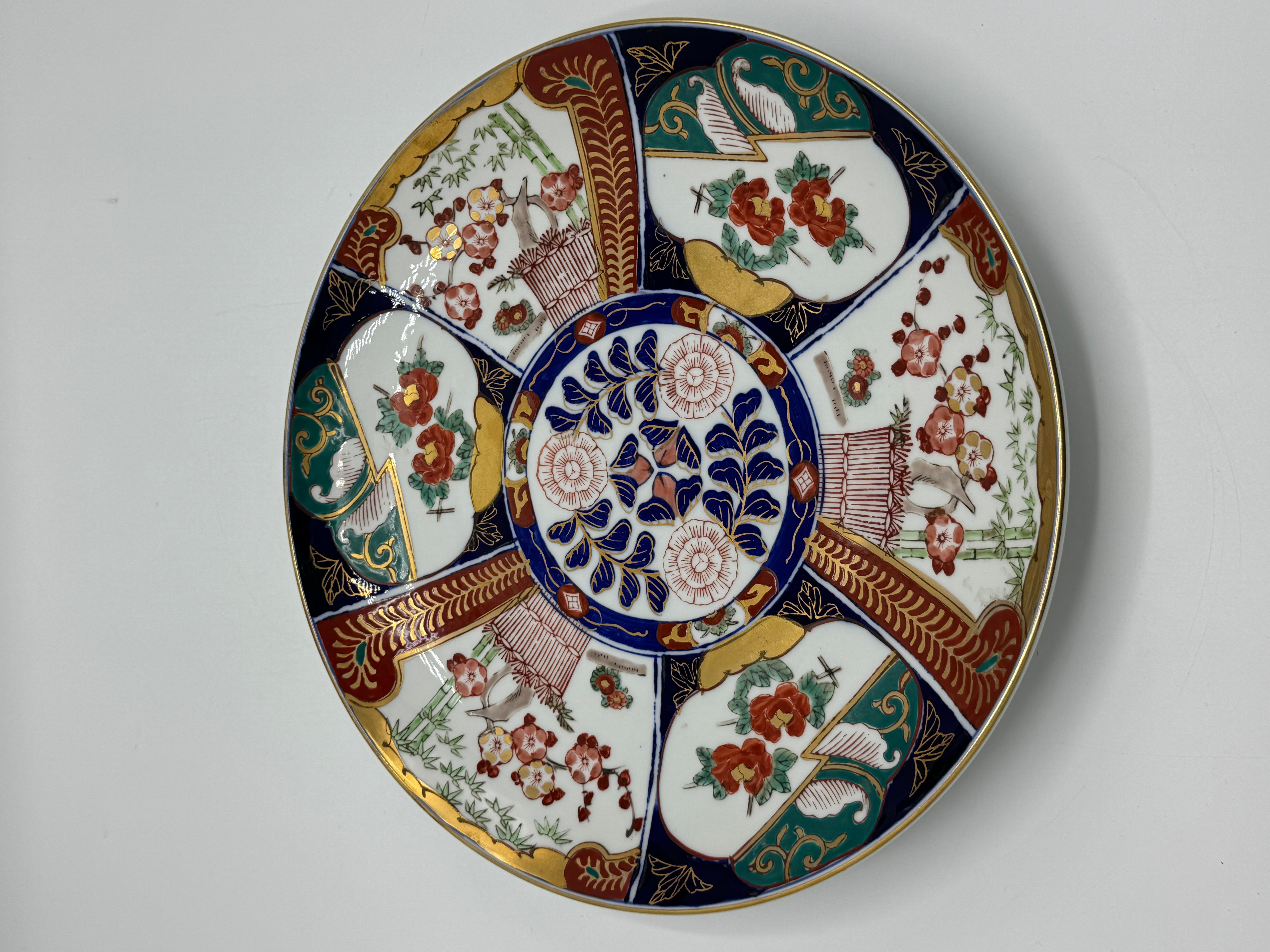 Listed is a stunning, 1970s Gold Imari polychrome decorative plate/charger. Featuring, a gorgeous, hand-painted oriental Chinoiserie scene, with gold accents. Three holes on backside, along the bottom (photographed), for plate hanger. Marked on