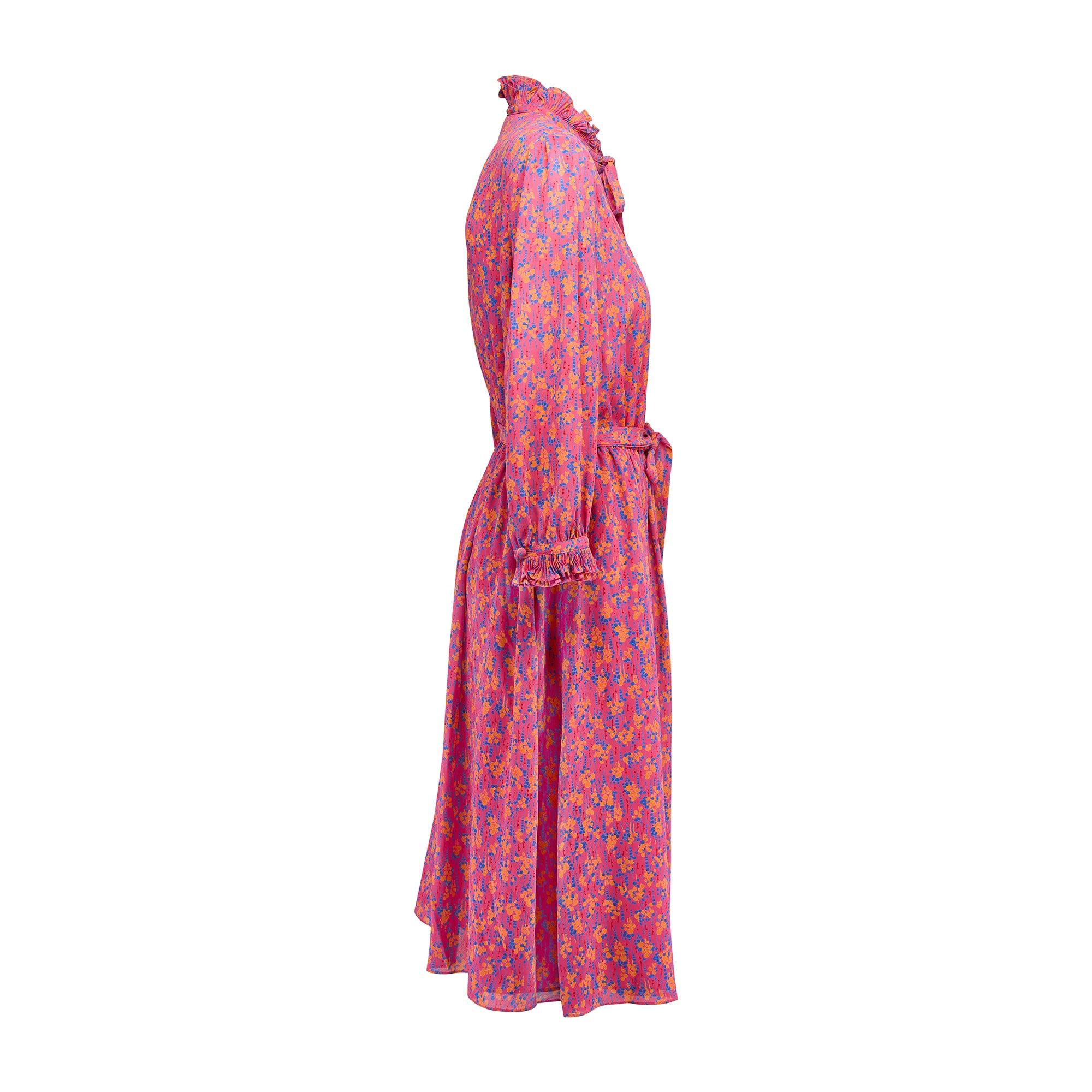 Este vibrante vestido fue diseñado por Tricoville en la década de 1970 como parte de su línea Gold Label. Confeccionado en un ligero crepé rosa chicle con un alegre estampado de flores abstractas, es una prenda que destaca por sí misma y puede
