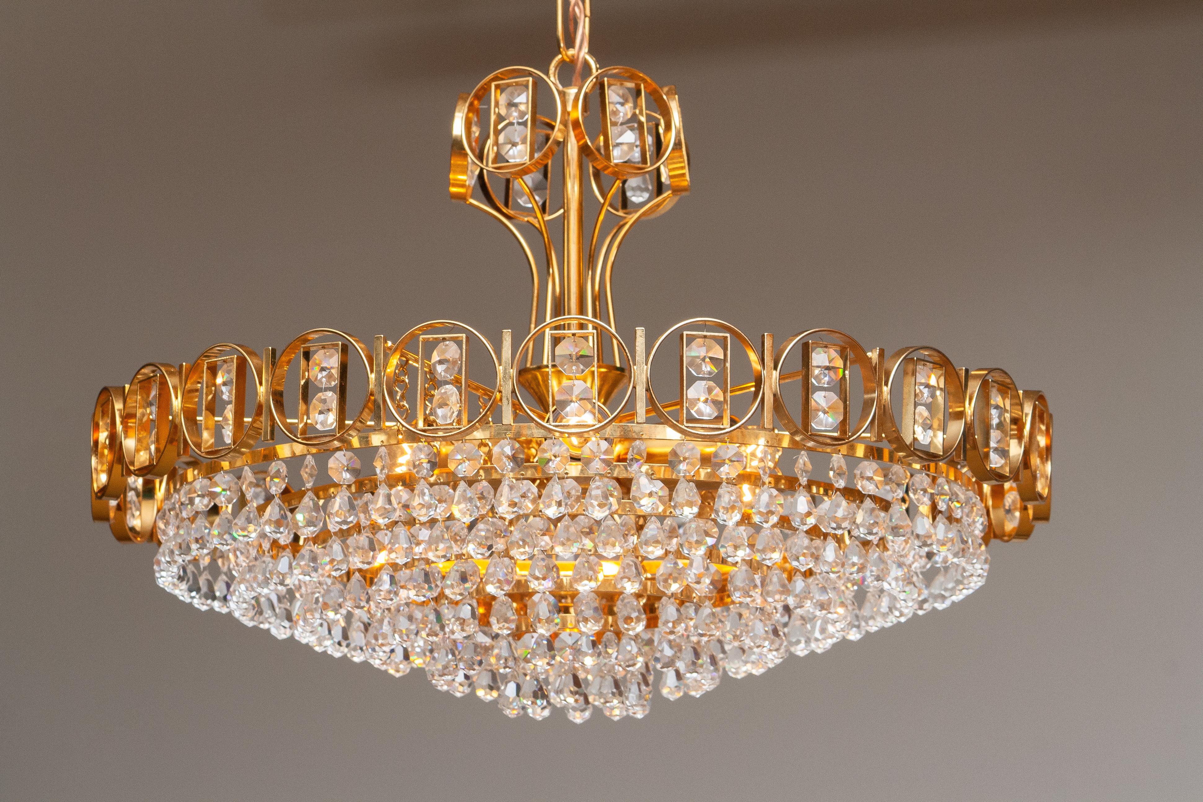 Beautiful brass gilded chandelier filed with faceted crystals made by Palwa Germany 1970.
This chandelier consist out of a gold plaited crown with inside six gold plaited rings filed with crystals and on top also a smaler gold plaited crown.
There