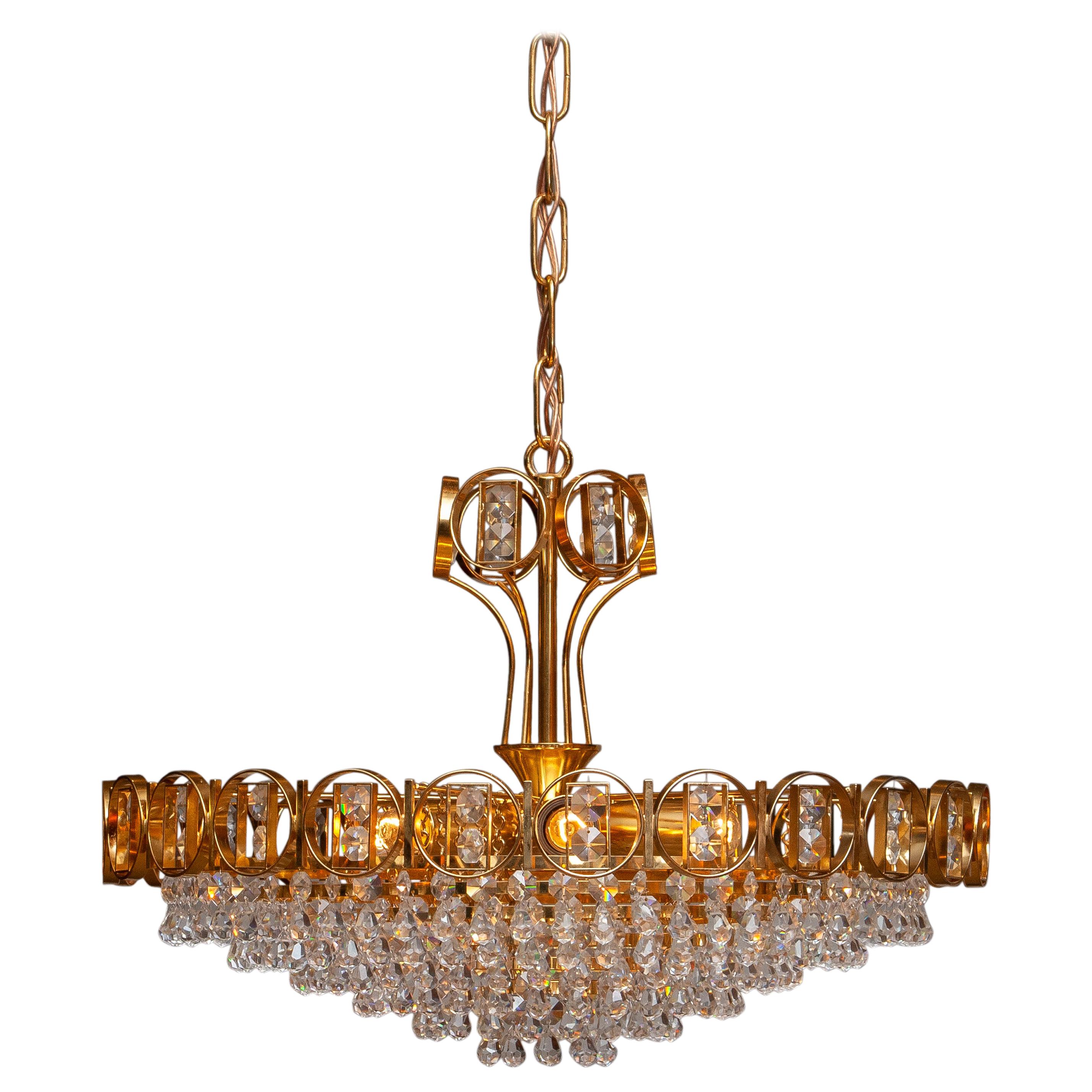 Beautiful brass gilded chandelier filed with faceted crystals made by Palwa, Germany, 1970.
This chandelier consist out of a gold plated crown with inside six gold plaited rings filed with crystals and on top also a smaller gold plaited