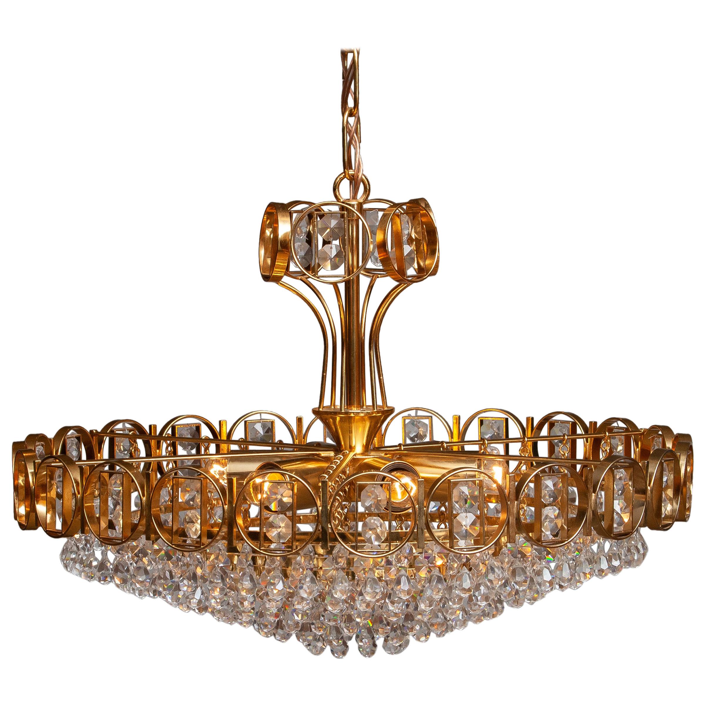 Beautiful brass gilded chandelier filed with faceted crystals made by Palwa, Germany, 1970.
This chandelier consist out of a gold-plated crown with inside six gold plaited rings filed with crystals and on top also a smaller gold plaited