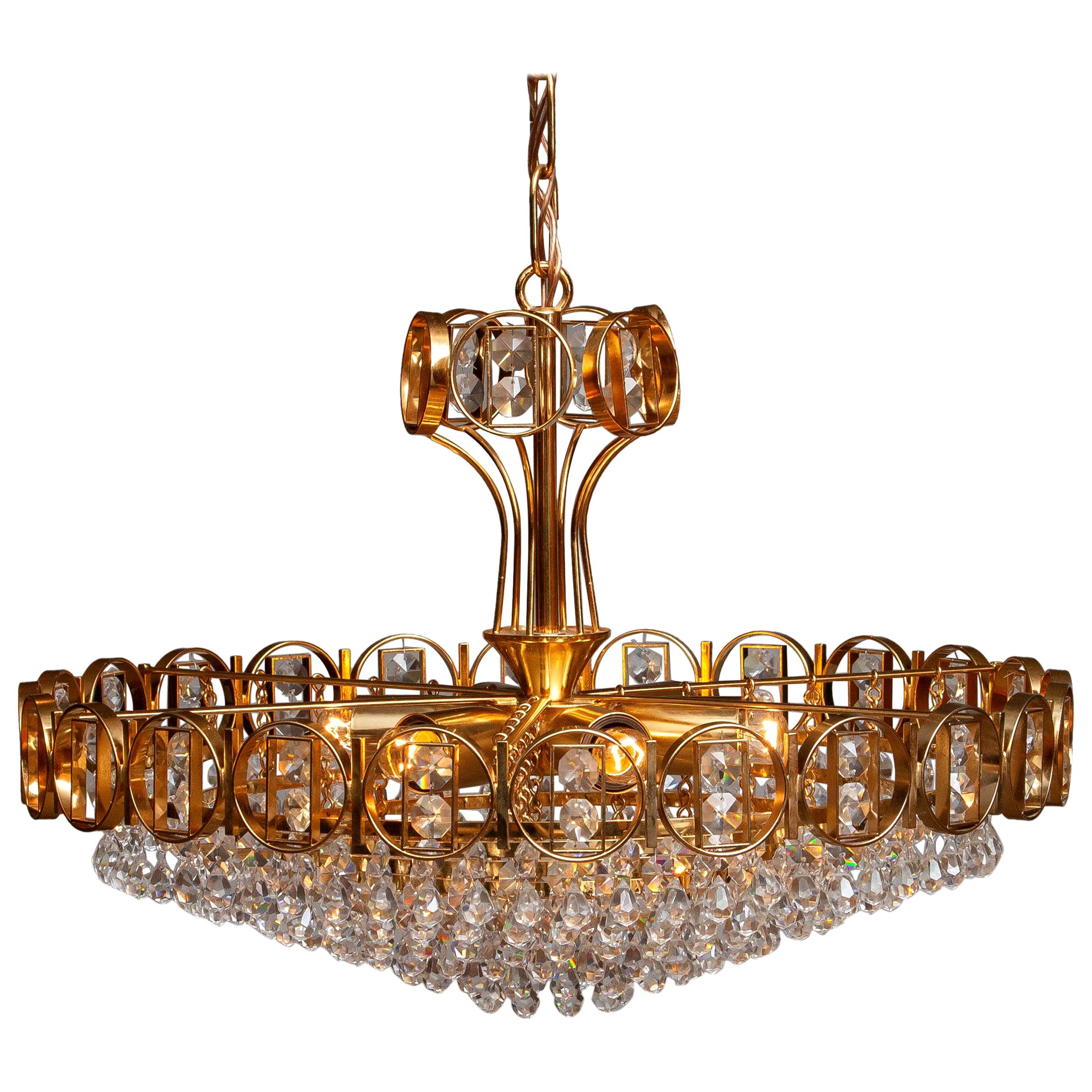 Beautiful brass gilded chandelier filed with faceted crystals made by Palwa, Germany, 1970.
This chandelier consists out of a gold-plated crown with inside six gold plaited rings filed with crystals and on top also a smaller gold plaited