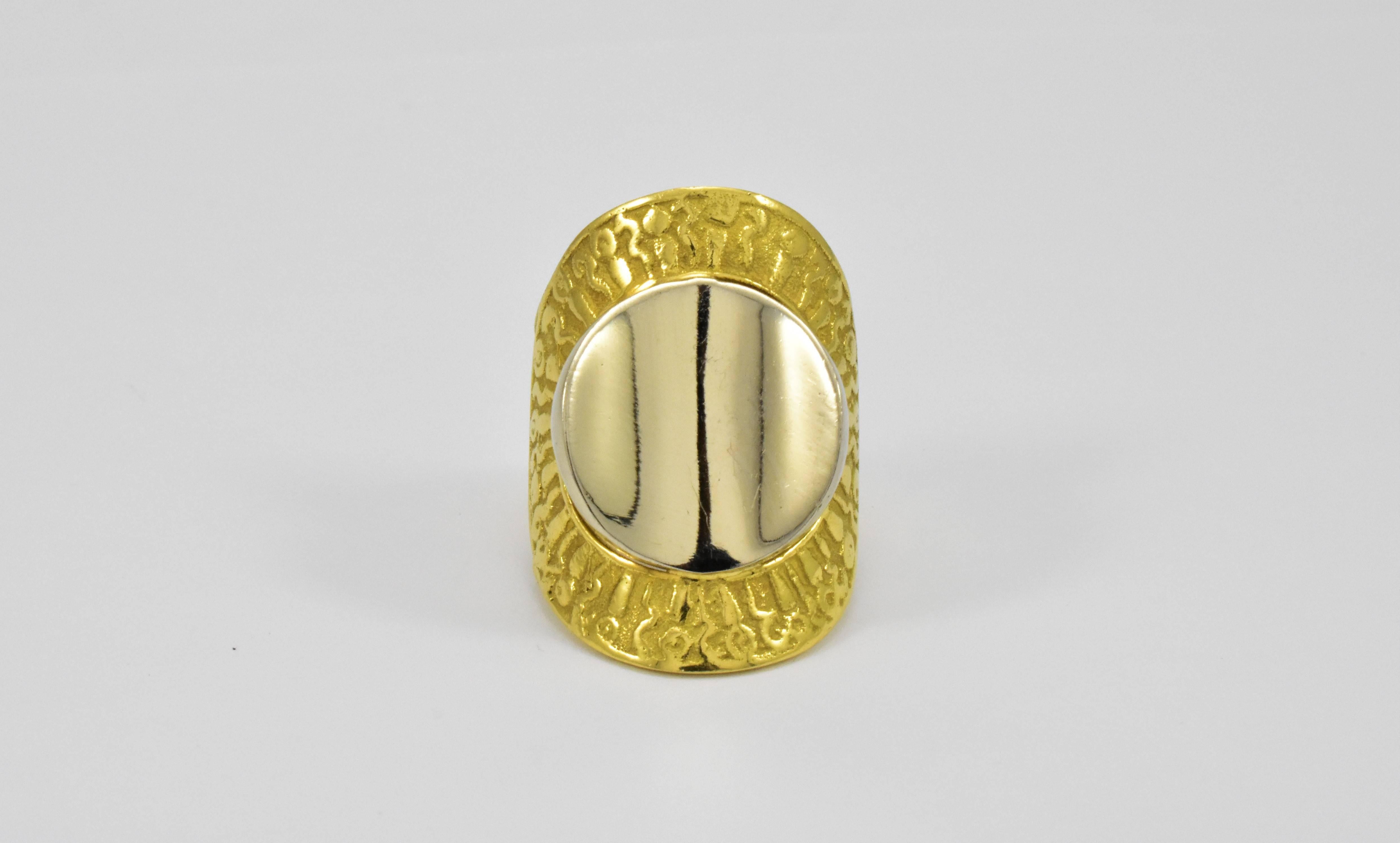 A large two tone white and yellow gold Greek revival style contemporary ring from 1970s. The ring features a central highly polished reflective concave white gold disc floating within yellow gold halo which has greek symbols details encircling the