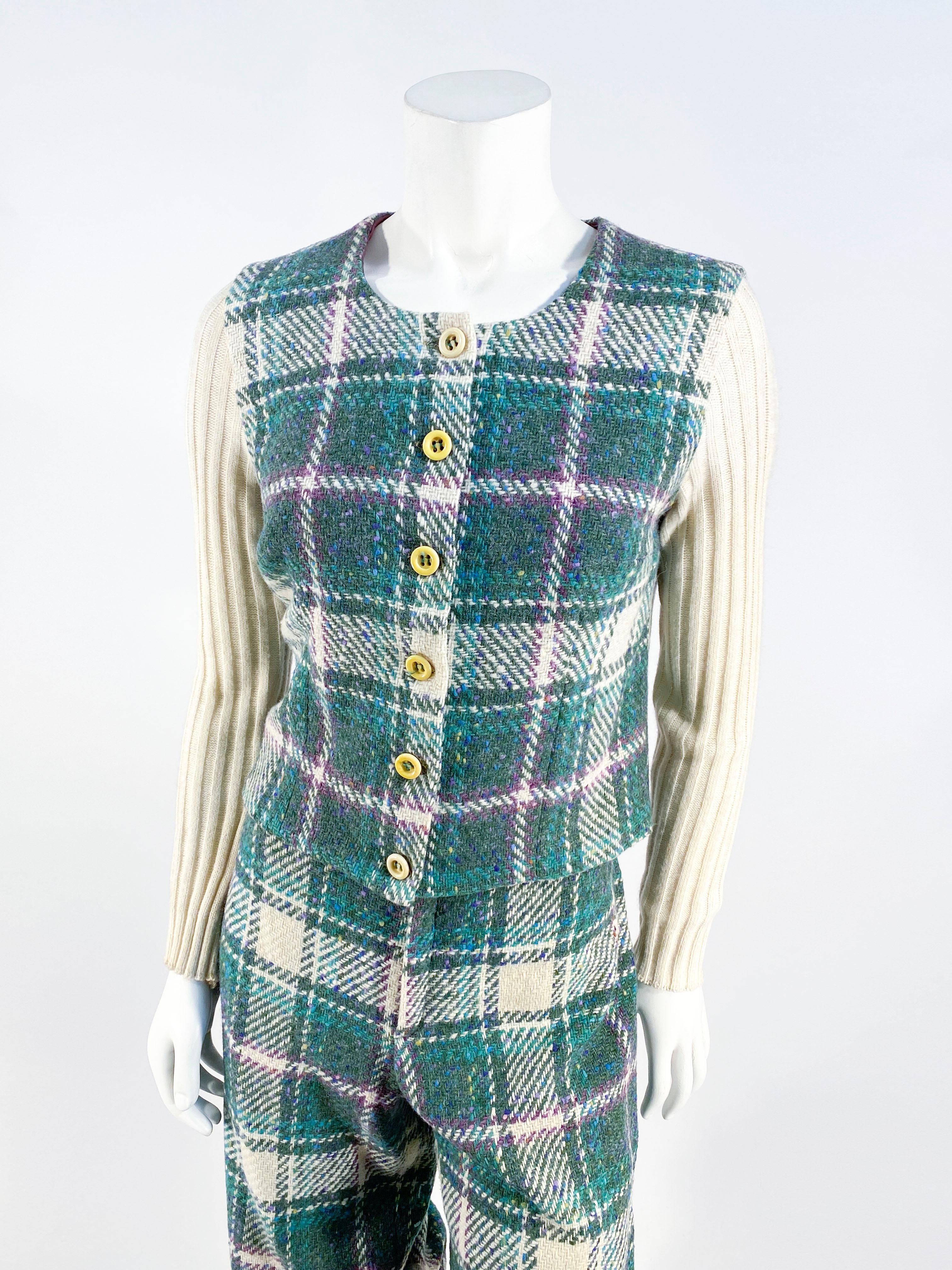 1970s wool sports set featuring a forest green plaid with stripes of purple and cream. The top has a front button down closure and cream ribbed knit full-length sleeves. The knickers have a hip hugger waist line, elastic at the knee, and is unlined.