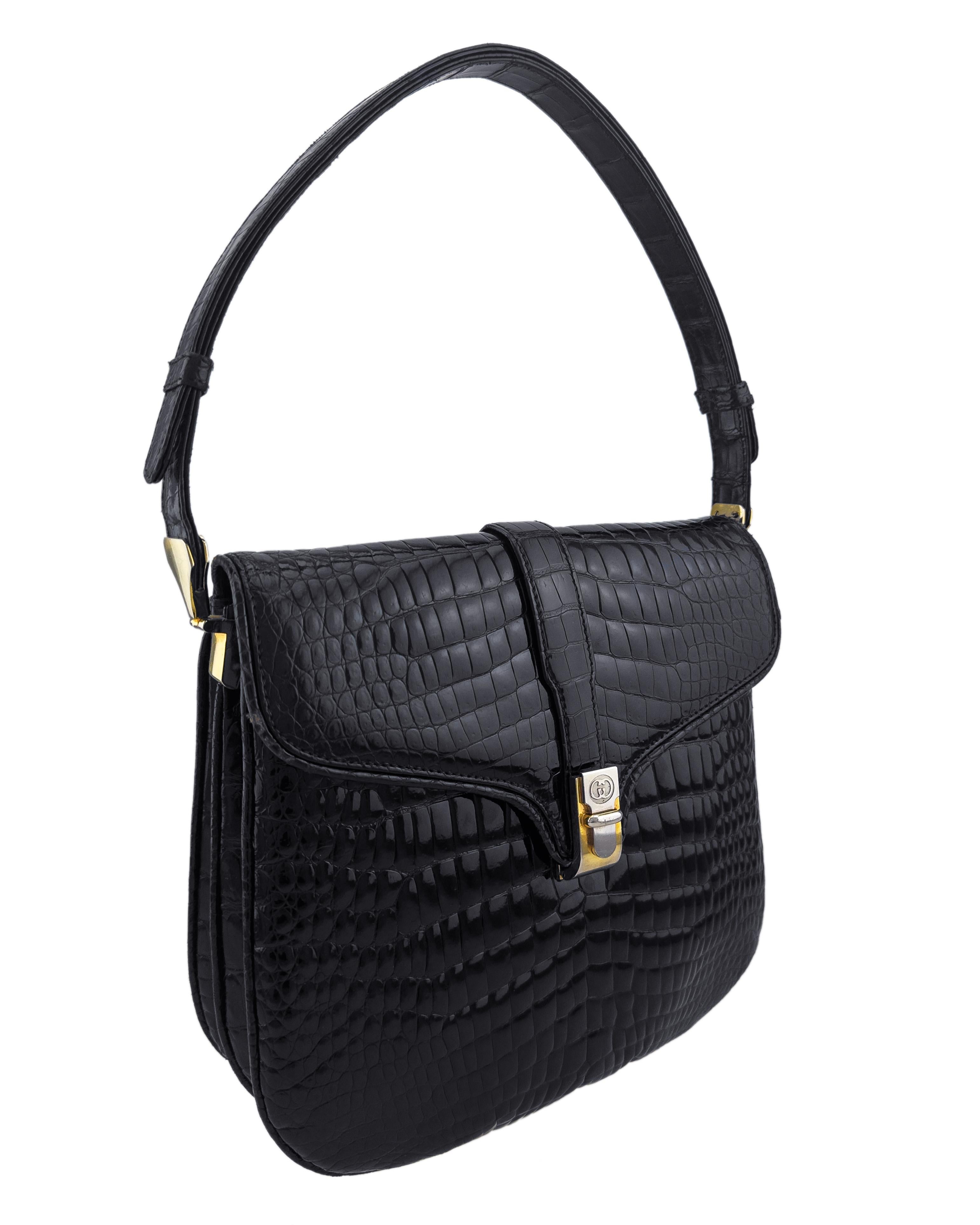 Dezenter Glamour trifft auf zeitlose Handwerkskunst bei dieser exquisiten schwarzen Gucci-Schultertasche aus den 1970er-Jahren aus Krokodil. Mit ihrem anmutig geschwungenen Überschlag und der stromlinienförmigen Silhouette erinnert diese Tasche an