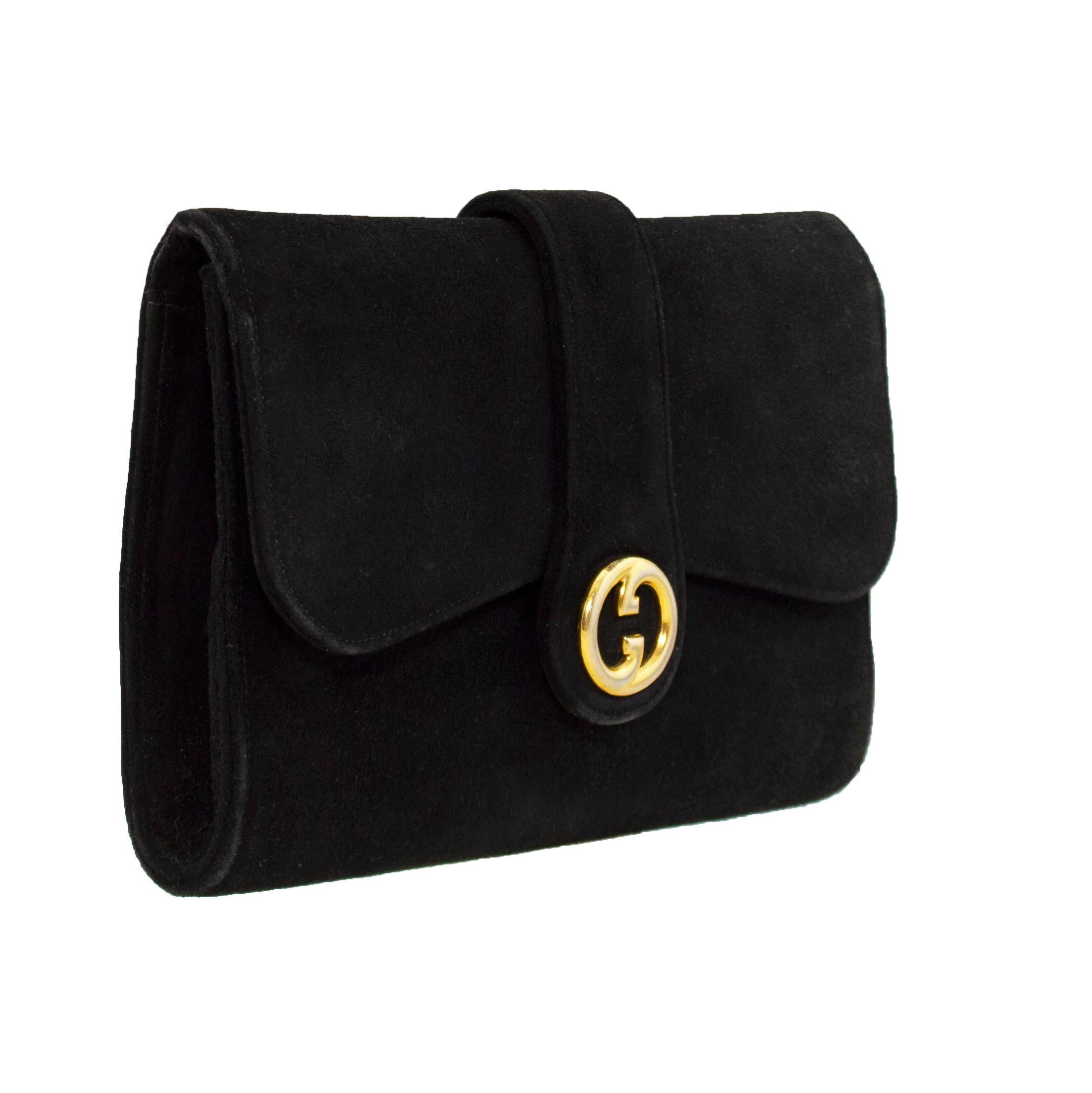 Gucci black suede evening clutch from the 1960s. Envelope shape with interlocking gold metal G logo at centre that conceal a snap closure. Black leather interior with two open slit pockets. A perfect and very versatile vintage clutch that is big