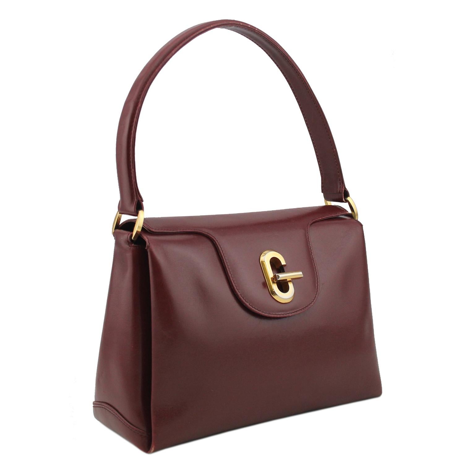 Gorgeous 1970s Gucci bag. Soft bordeaux leather with gold hardware. Large gold G with twist lock to open the flap. Interior features three compartments and a single flat pocket with zipper closure. Clean interior, black lining. Gold Gucci interior