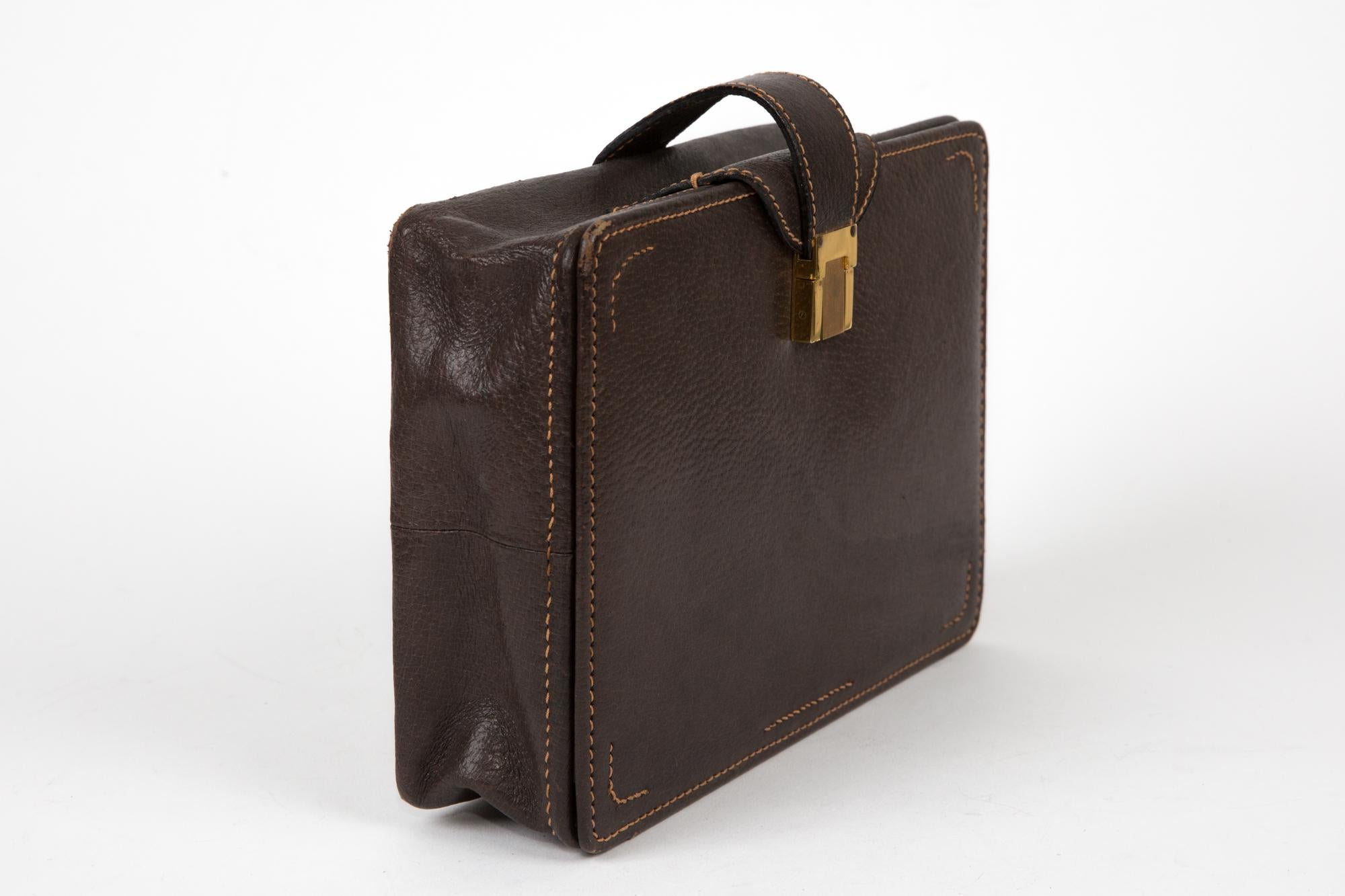 Reisekoffer aus braunem Leder von Gucci aus den 1970er-Jahren mit einer Öffnung mit goldfarbenen Klammern, Nylonfächern im Inneren und einem goldfarbenen Stempel. 
Länge 9,4 Zoll (24 cm)
Höhe: 17 cm (6,7 Zoll)
Breite: 6 cm (2,3 Zoll)
In gutem