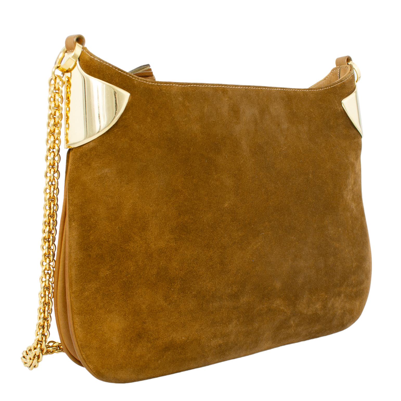 Stunning 1970s Gucci shoulder bag. Caramel brown suede with bright gold tone metal accents and hardware. Saddle shape with heavy and thick chain shoulder strap. Plastic top zipper with tassel zipper tab. Large single compartment suede interior with