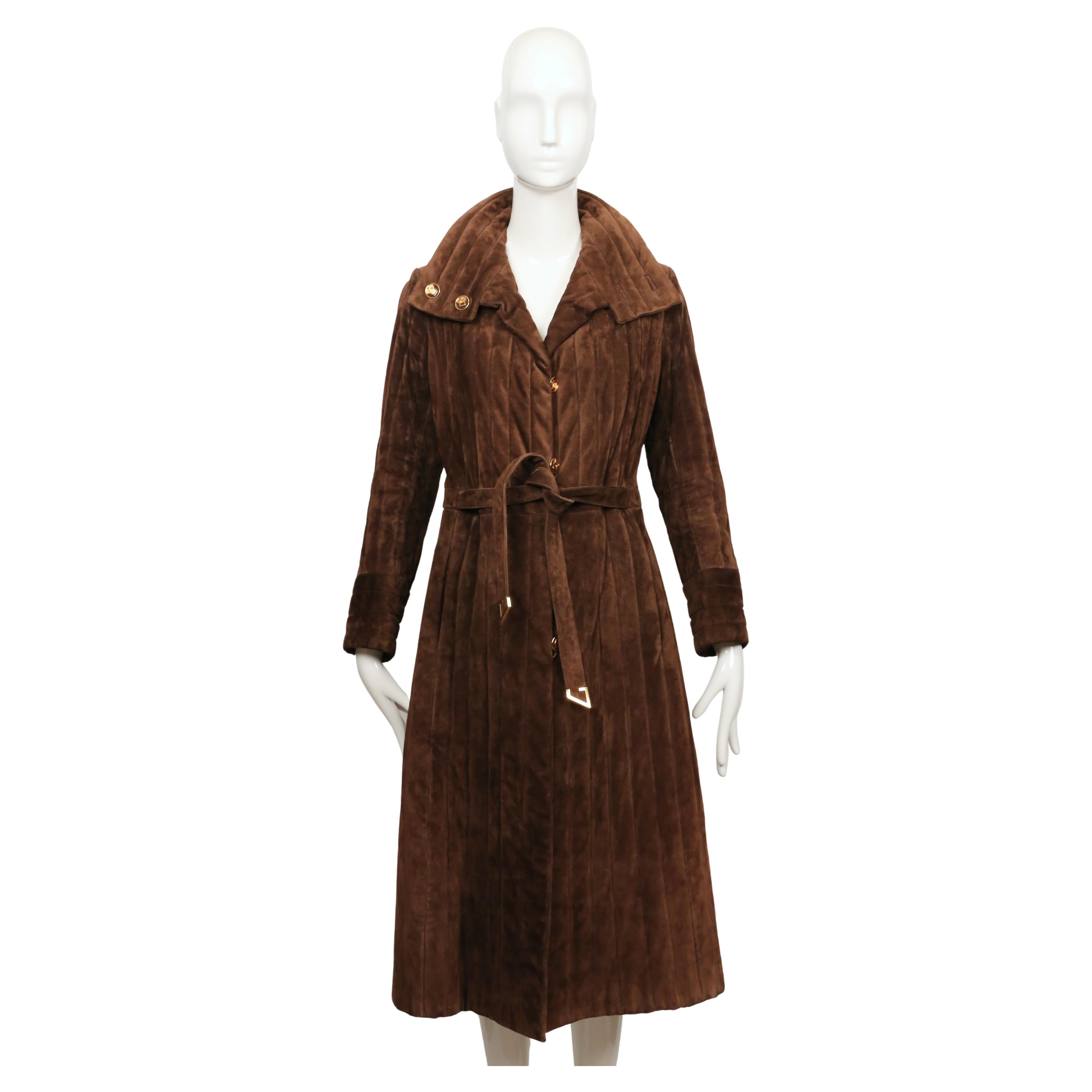 Un cappotto Gucci in pelle scamosciata marrone degli anni '70, tagliato con una linea ad A morbidamente strutturata e trapuntato con lunghi canali verticali che gli conferiscono peso e consistenza. Il colletto è ampio e rifinito con due bottoni