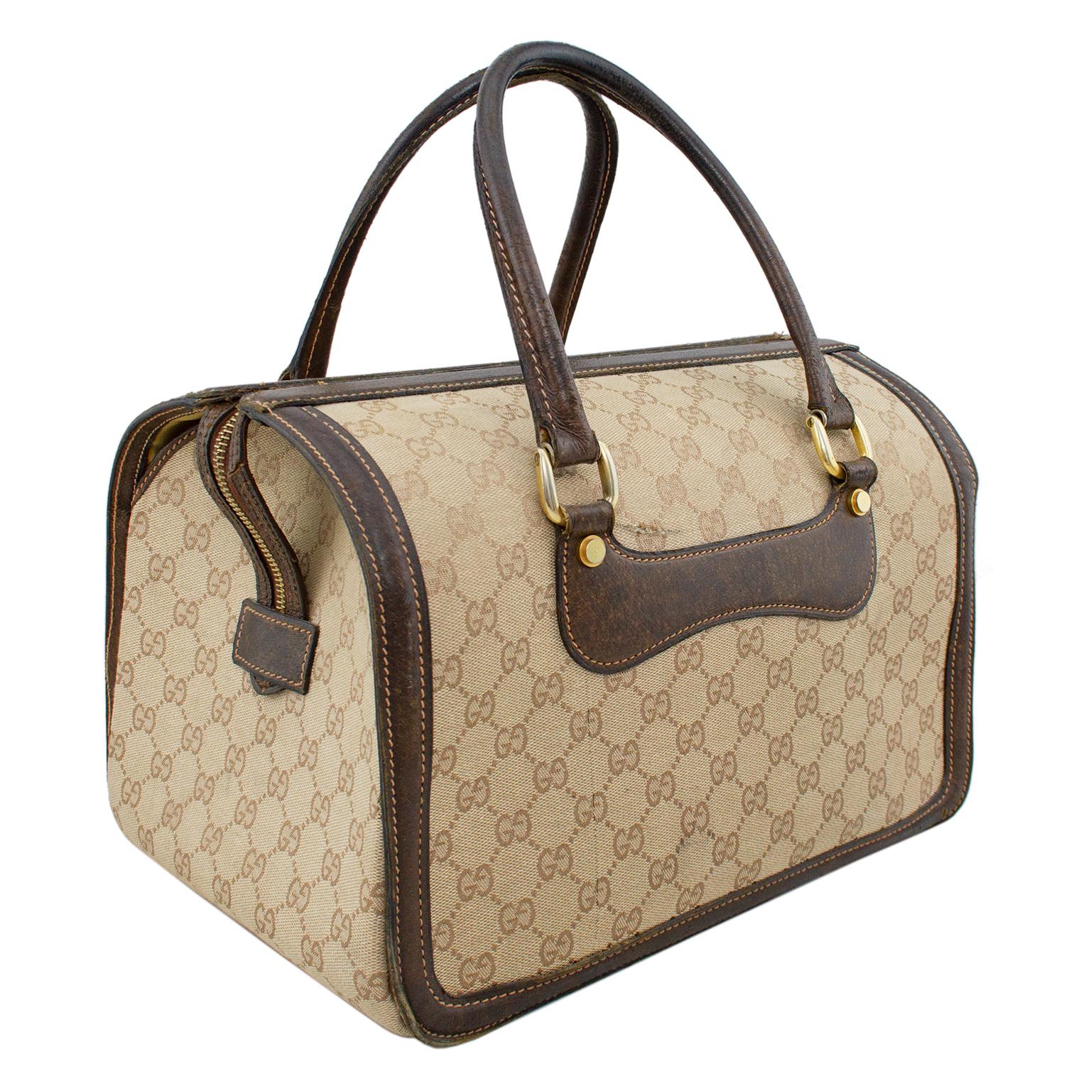 Travel in style with this 1970s Gucci hard vanity train case. Beige monogram canvas with dark brown leather trim and double handles. Boston style shape with a zipper across the top. Long brown leather zipper tab folds over the side and locks into