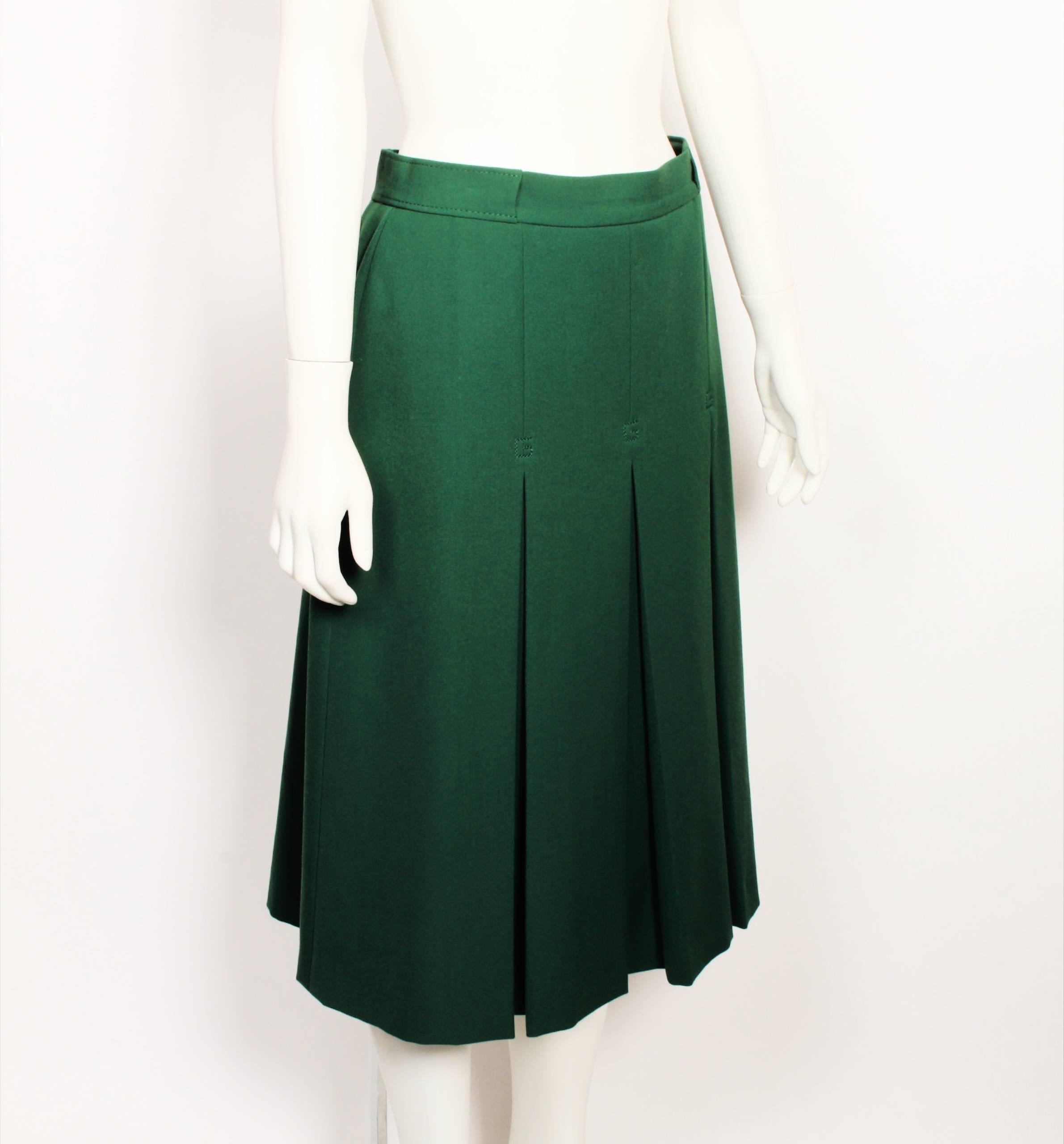 1970's Gucci moss green wool twill mid length skirt features 3 inverted front pleats from the hip point. 
The top of each pleat is decorated with a double stitched G. The fitted waistband has a channel on the sides for a belt or scarf. Fully lined