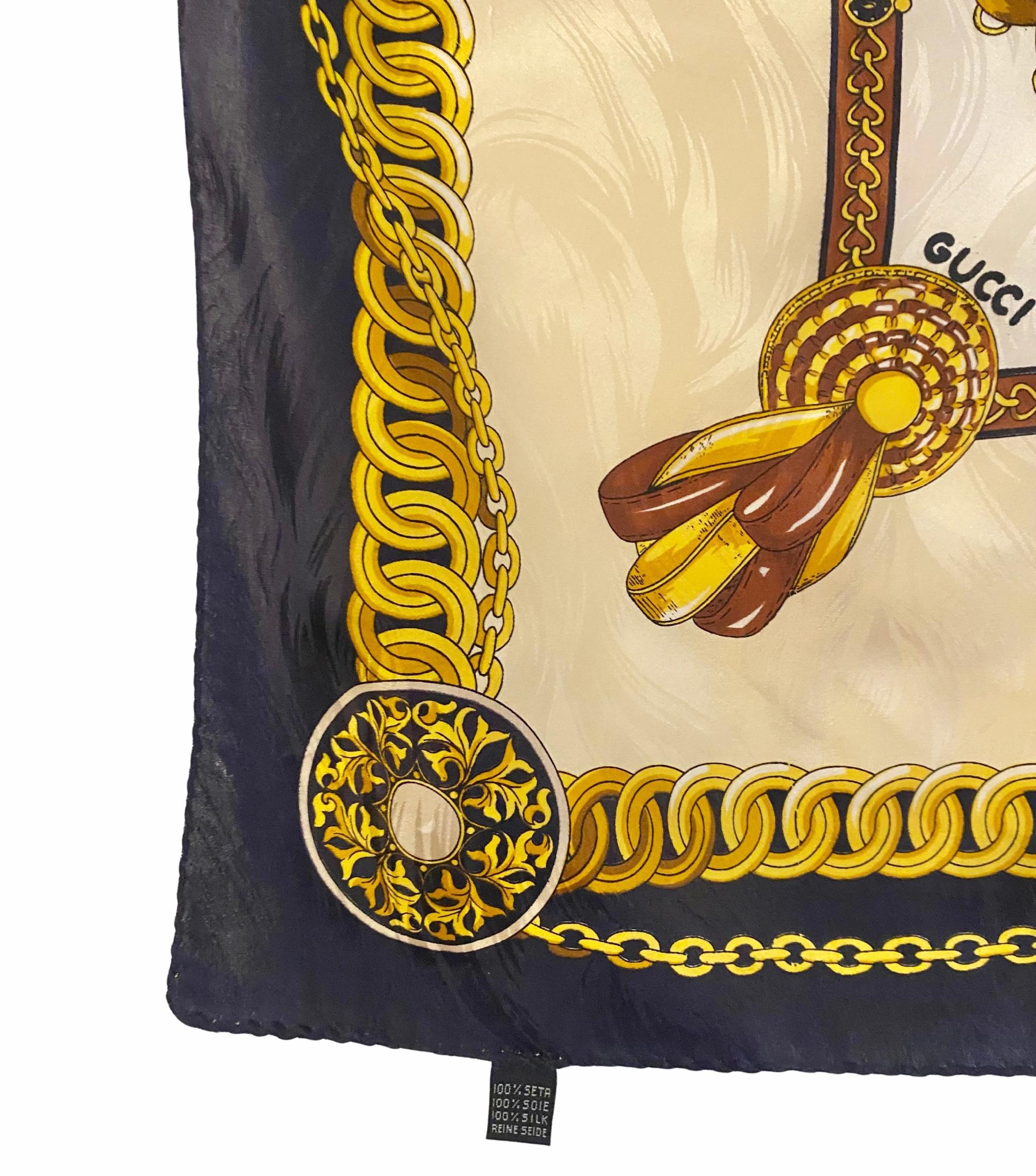 Il foulard Gucci degli anni '70 sfoggia una tavolozza di colori blu e oro con briglie, punte, catene decorate, rosette e medaglioni disposti in modo perfettamente simmetrico. Realizzato in Italia in 100% pura seta, offre una texture liscia e