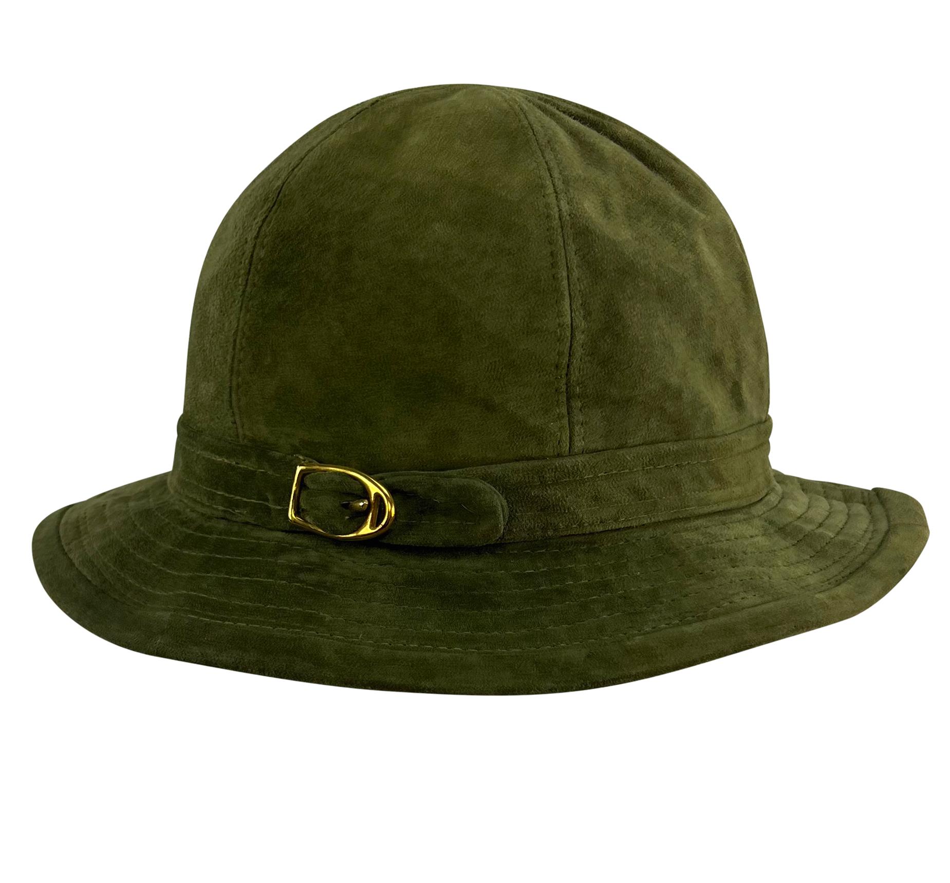 Dieser schicke Gucci Eimerhut aus den 1970er Jahren ist komplett aus weichem olivgrünem Wildleder gefertigt. Der Hut hat eine gesteppte Krempe und einen goldfarbenen Steigbügel-Akzent und passt perfekt zum Trenchcoat, der ebenfalls in unserem Shop