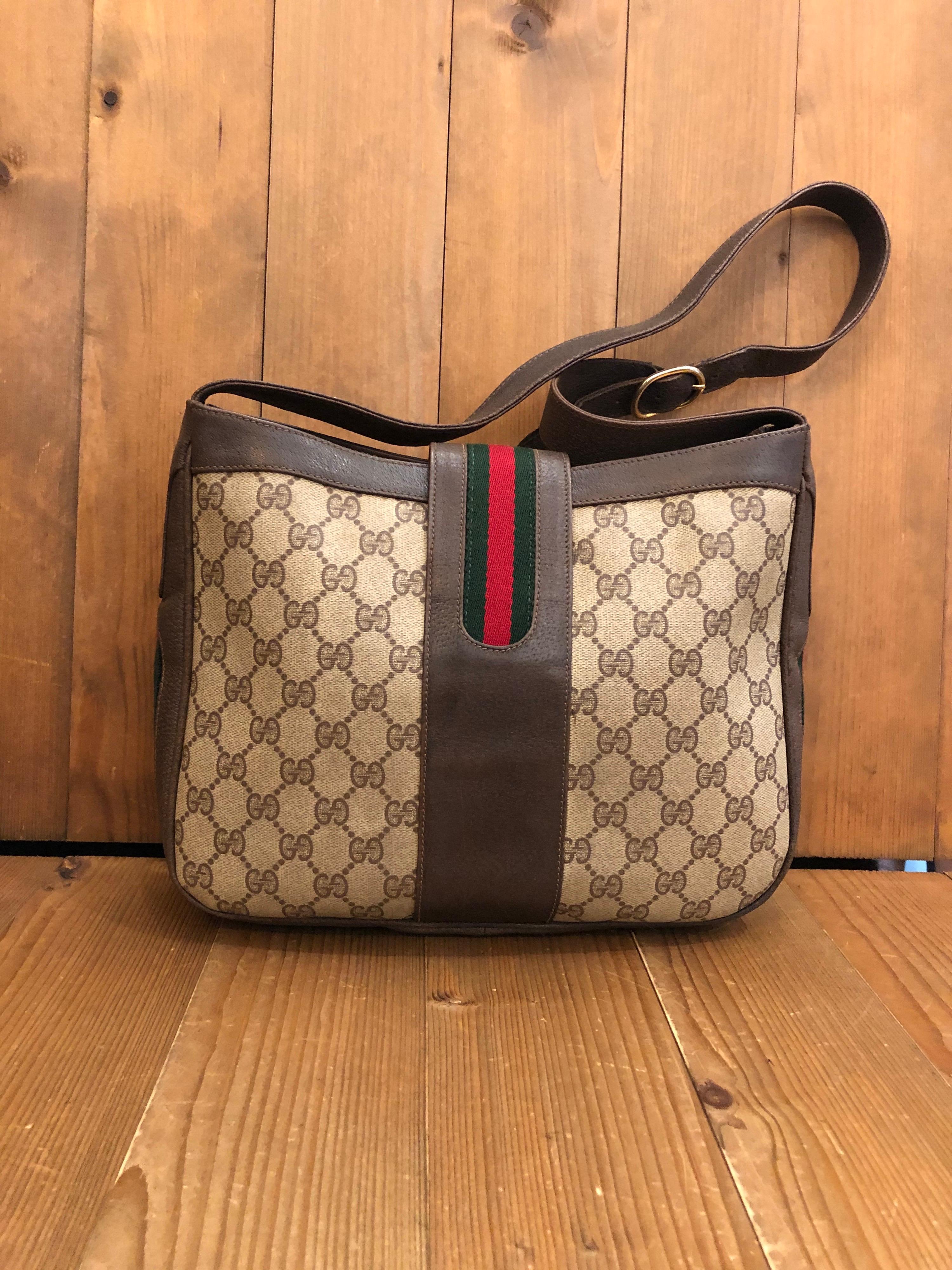 This rare vintage GUCCI Web Shoulder Bag  is crafted of monogram canvas in brown trimmed with brown leather adorned with Gucci’s iconic red/green stripe. Front flap snap closure decorated with equestrian boots motif opens to a beige leather interior