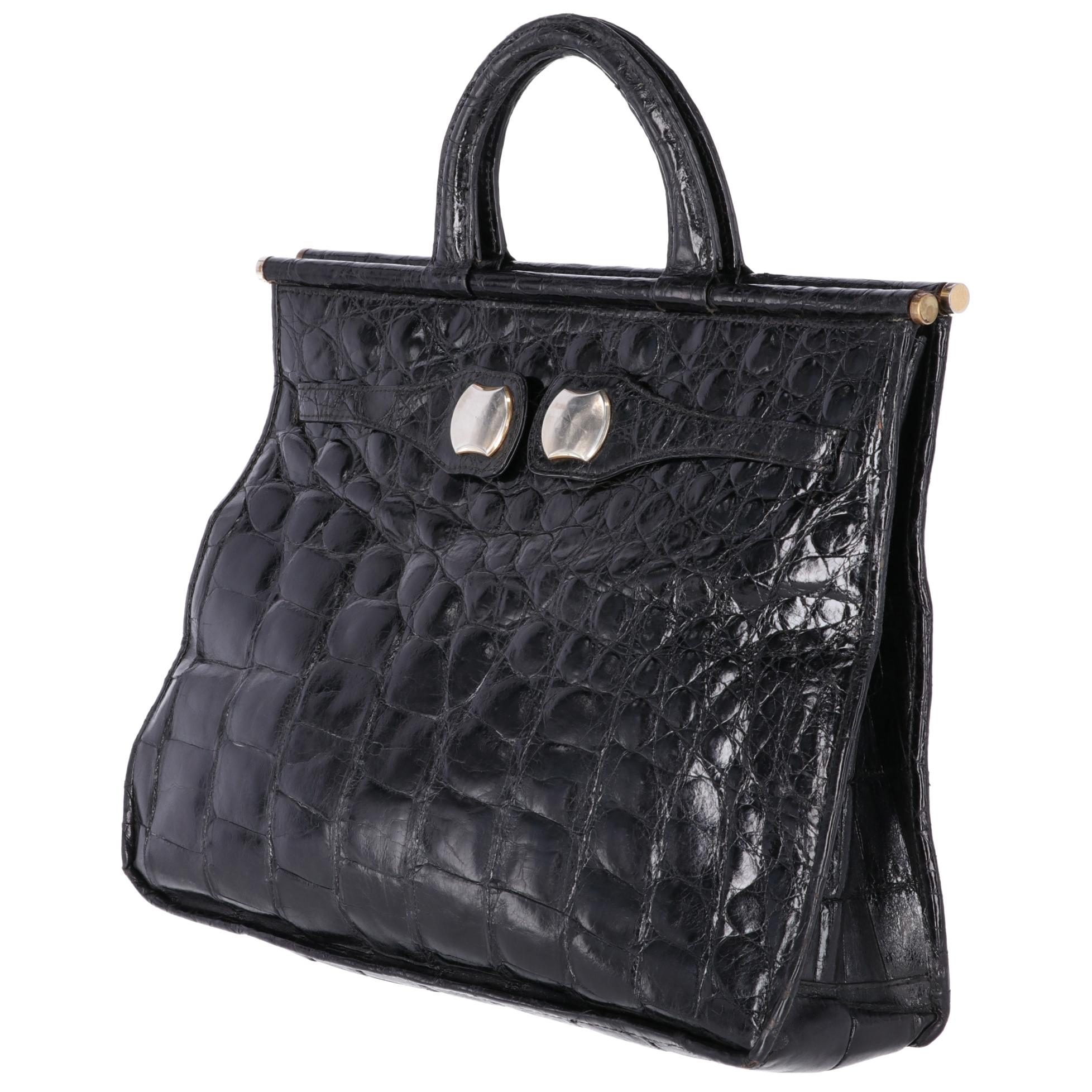 Black polished crocodile skin tote bag, with round and rigid handles, front closure with two tapes with magnetic metal insert, large internal compartment and two pockets, one with a snap button and one with a zip.

The bag shows light signs on the