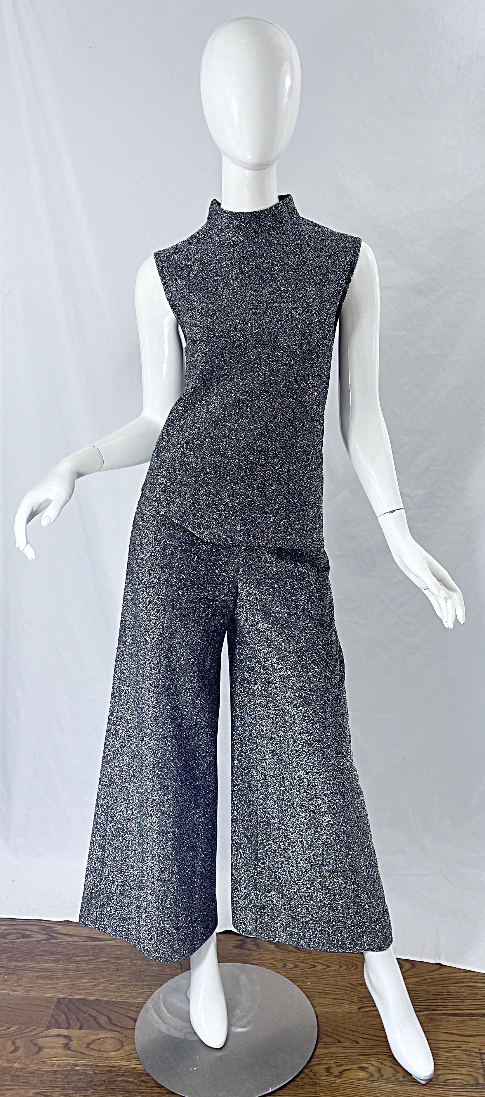 Amazing vintage 70s SUSAN THOAS gunmetal silver metallic top and wide leg palazzo pants ensemble ! Top has a high neck and metal zipper up the center top back. High waisted palazzo pants feature a metal zipper up the center back with hook-and-eye