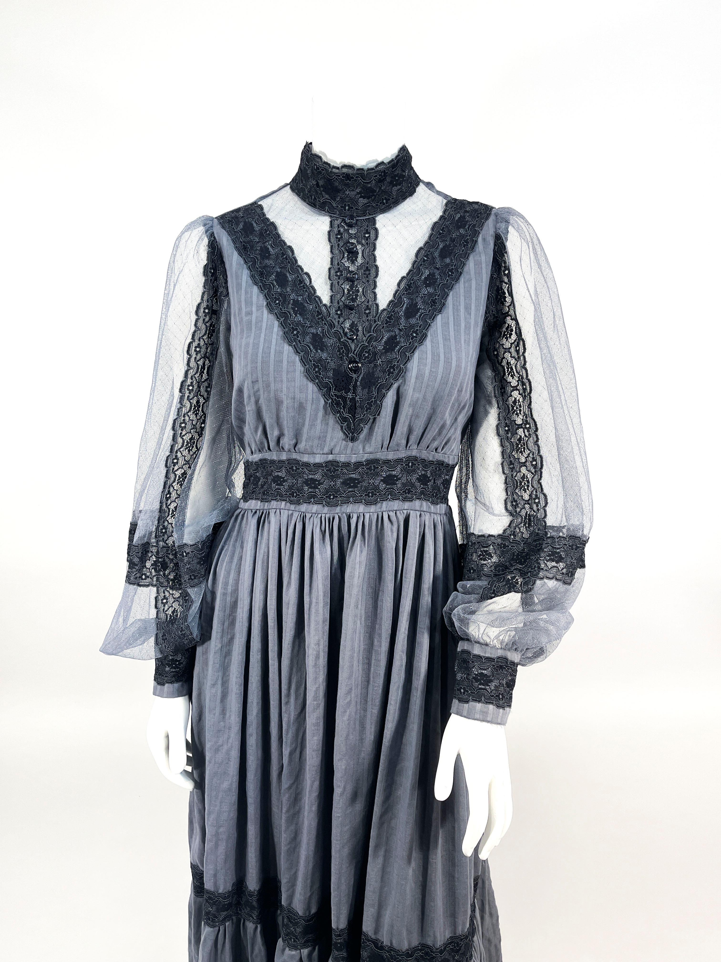 1970s Gunnel Sax overdid grey/blue cotton prairie dress with black lace trim throughout. The bishop cuffed sleeves are made of  a sheer mesh along with it s high neckline. The full length skin has a tiered and wide ruffled hem and the waist has a