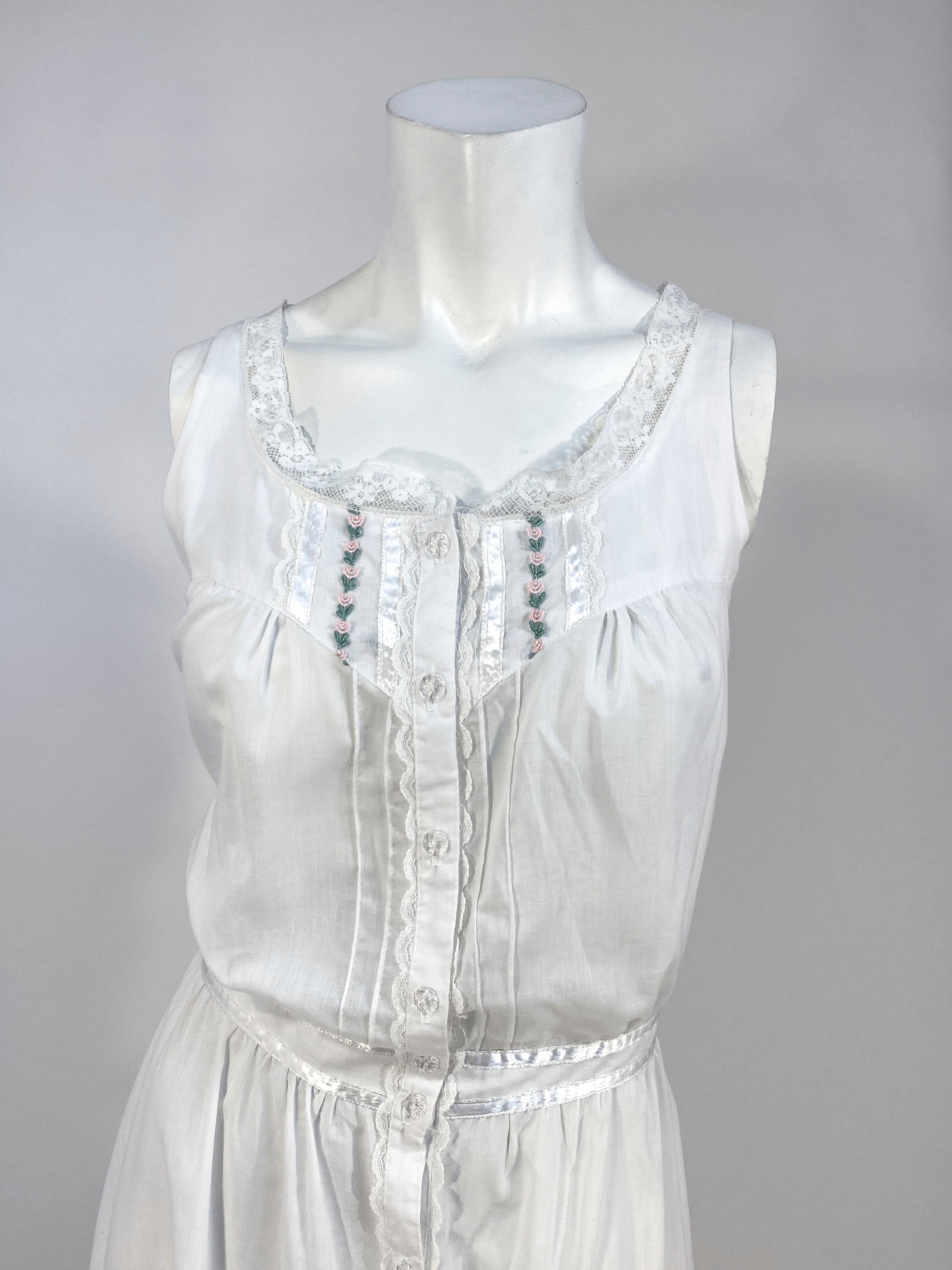 1970s Gunne Sax white cotton day dress with machine lace trim/embroidery, clear button front closure, pin pleats, gathers, wide ruffled hem, and a double piped waist with adjustable attached sash .