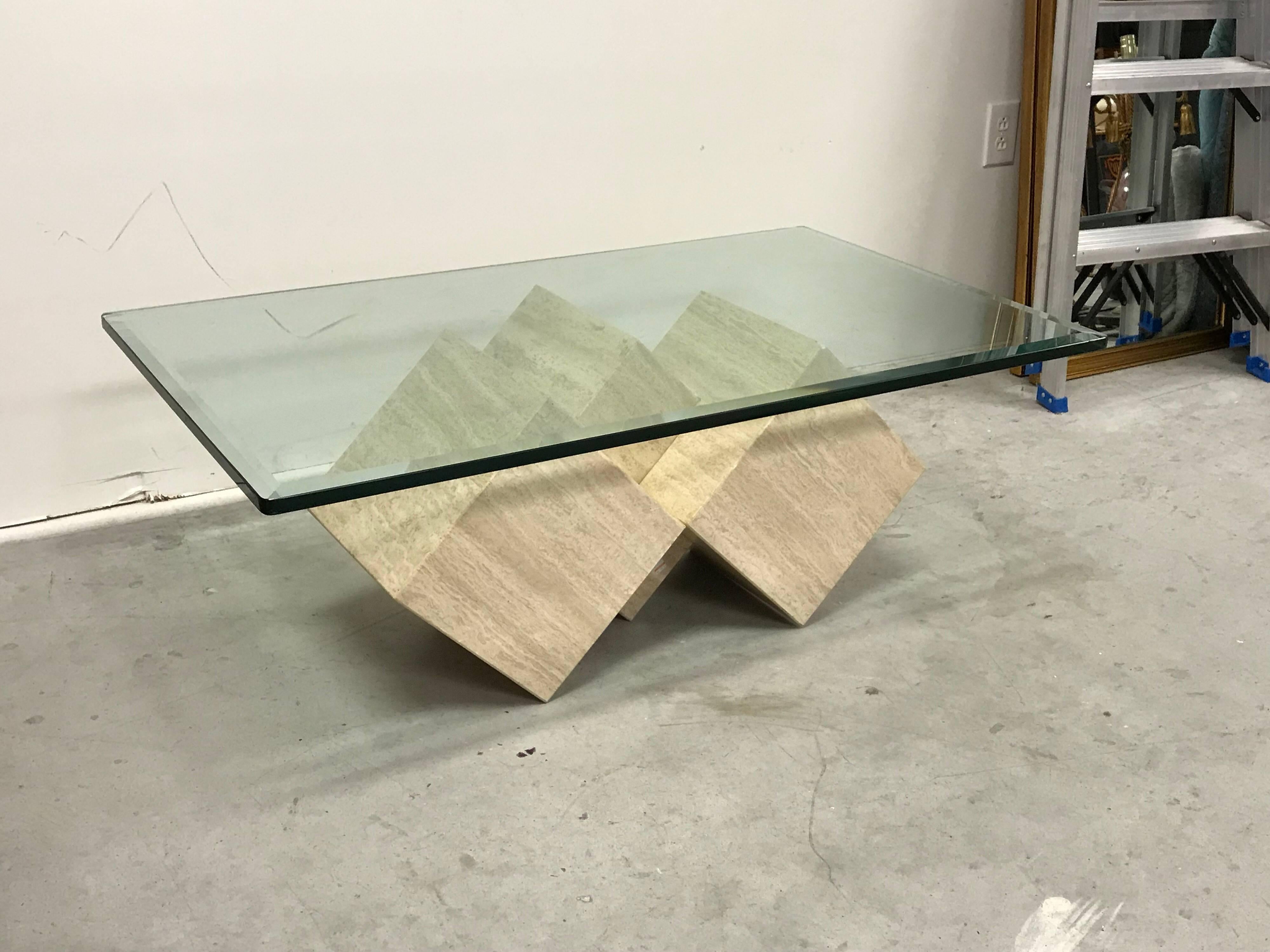 Offered is a stunning, 1970s Italian travertine cube coffee table by Guy Barker for Ello Furniture Company. The piece has a thick, weighted glass top rested upon three interlocked travertine cubes. The base can be repositioned in several ways, see