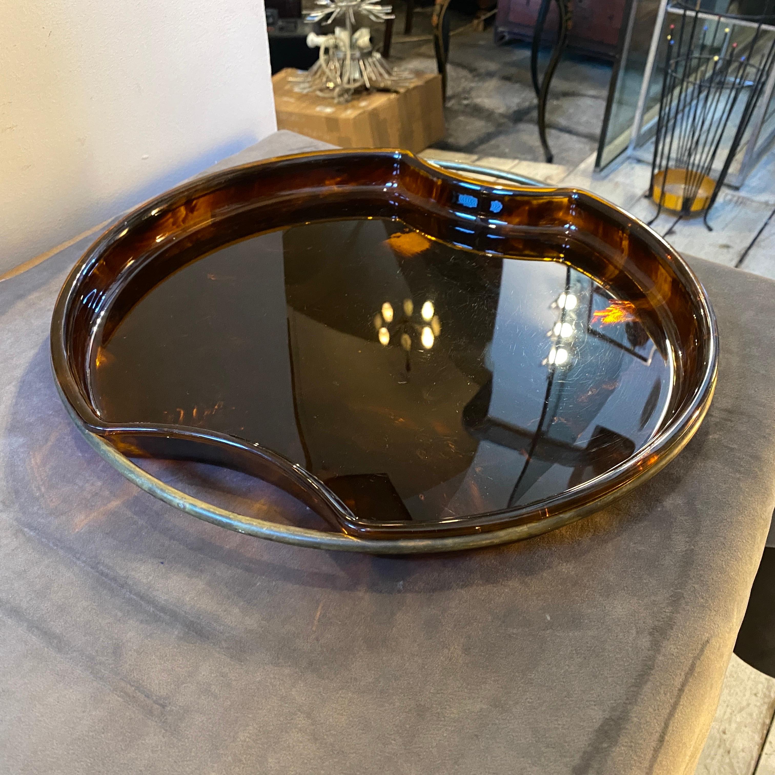 An iconic round tray by Guzzini made in Italy in the Seventies, fake tortoise lucite it's in very good conditions, brass it's in original patina.