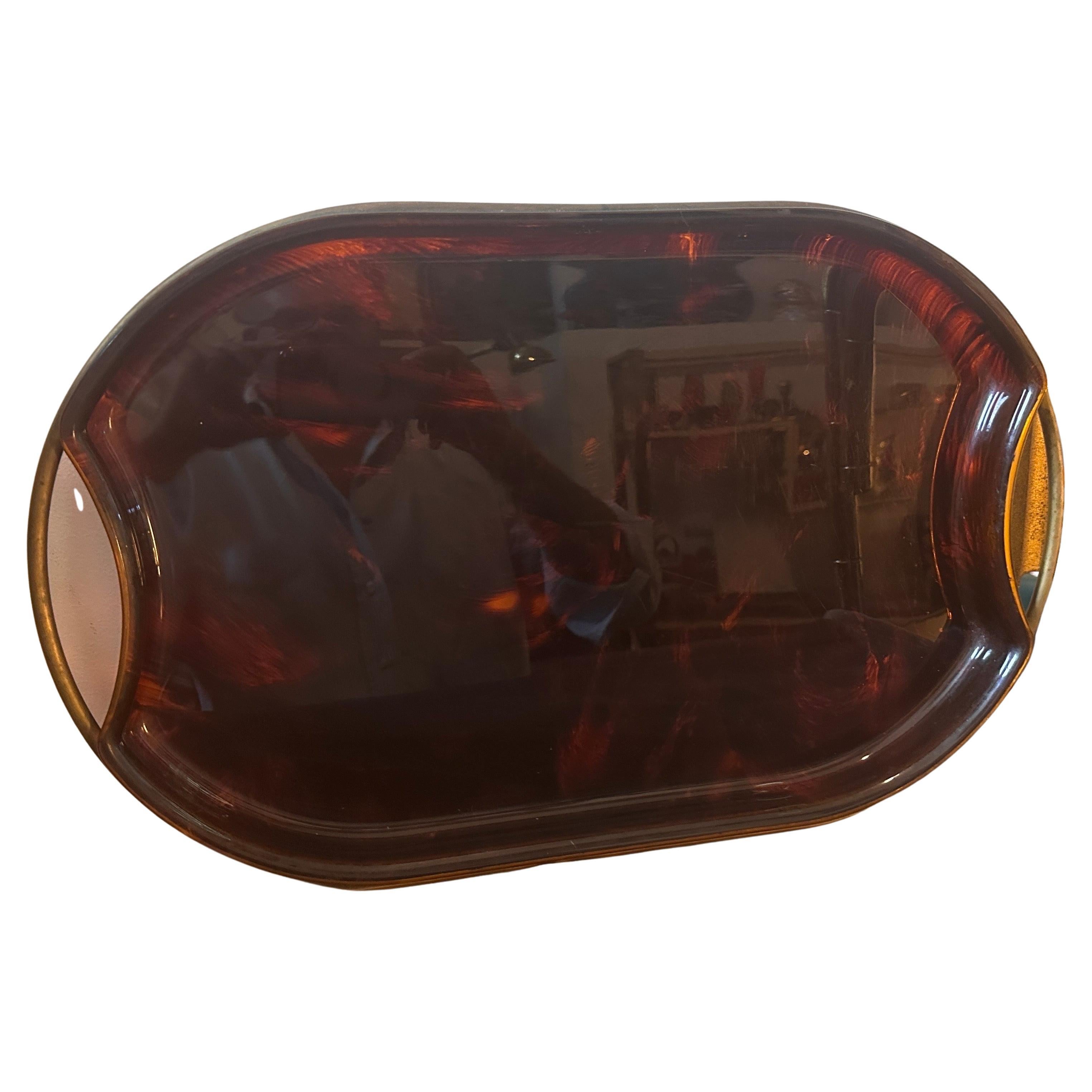 A Modernist Fake Tortoise Lucite and Brass vintage tray, designed and manufactured by the Italian design company Guzzini during the 1970s, is in lovely condition. The Guzzini company is a well-known Italian brand that specializes in the production