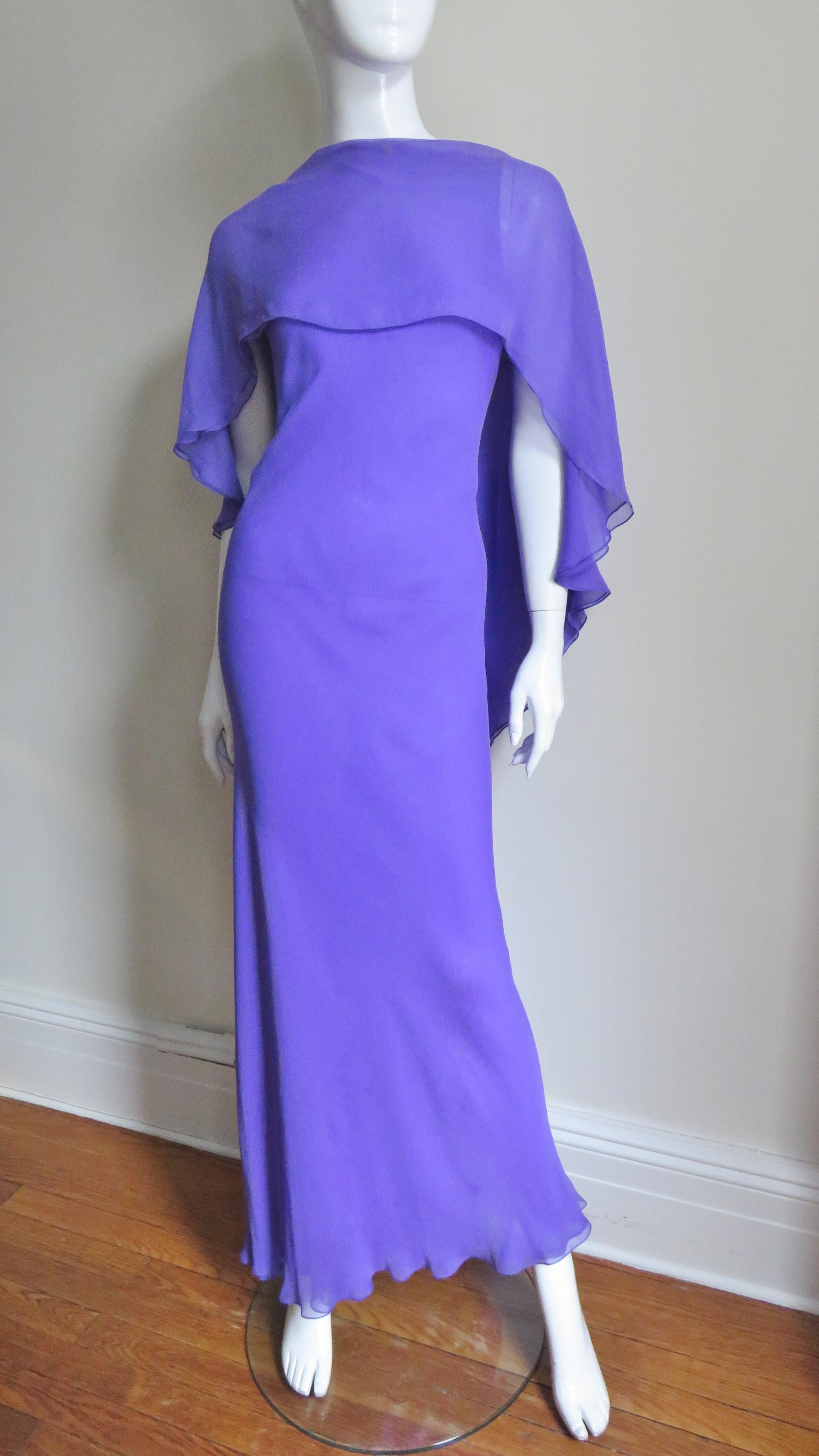 A gorgeous purple silk dress by Halston. It is a sleeveless semi fitted long sheath with a panel across the front chest and shoulders angling and widening towards the center back framing a deep V then continuing to the hem creating cape effect.  The